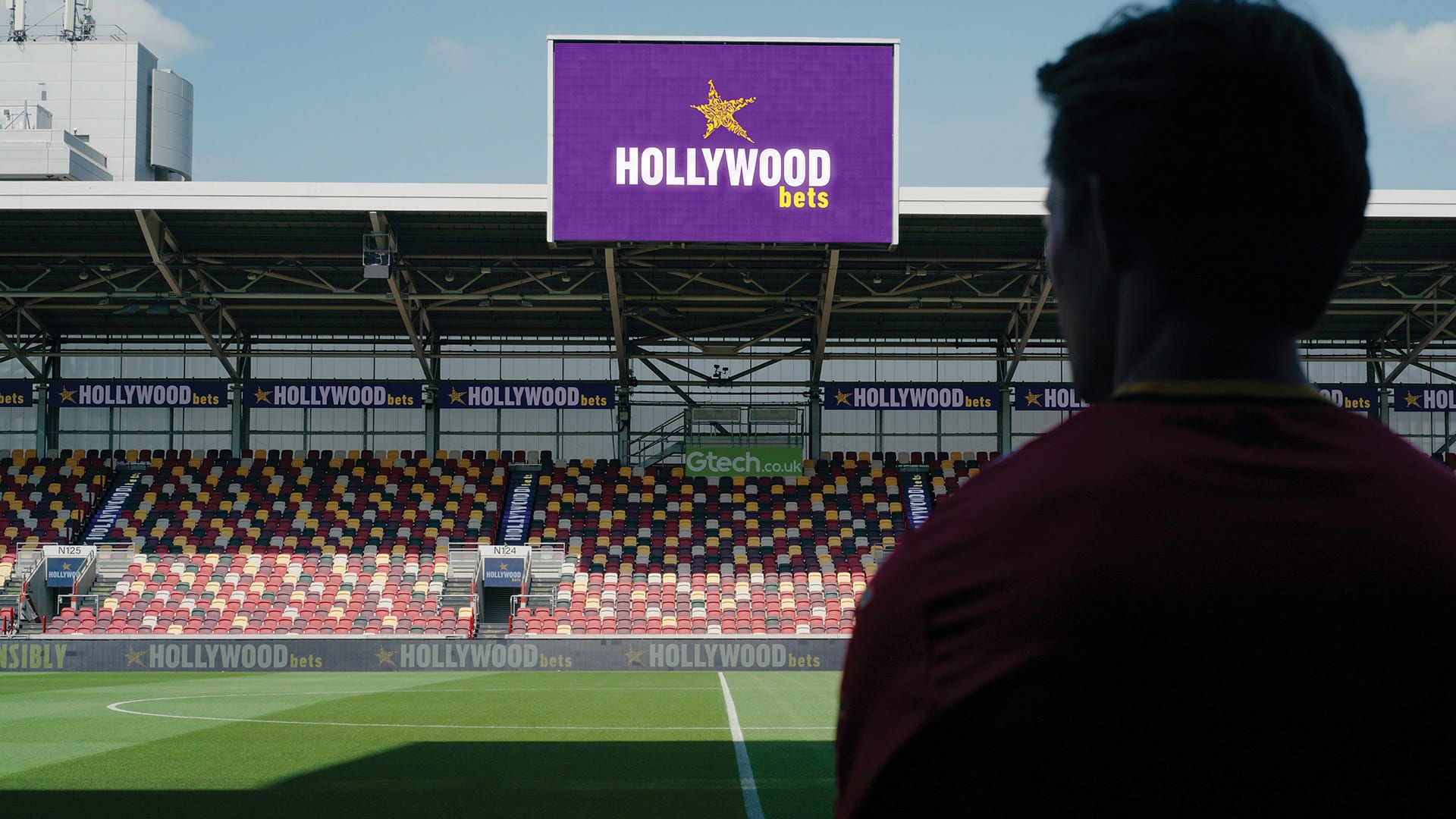 Brentford's Gtech Community Stadium with Hollywoodbets branding on the big screen and LED boards, showing the club's sports sponsorship in the stadium