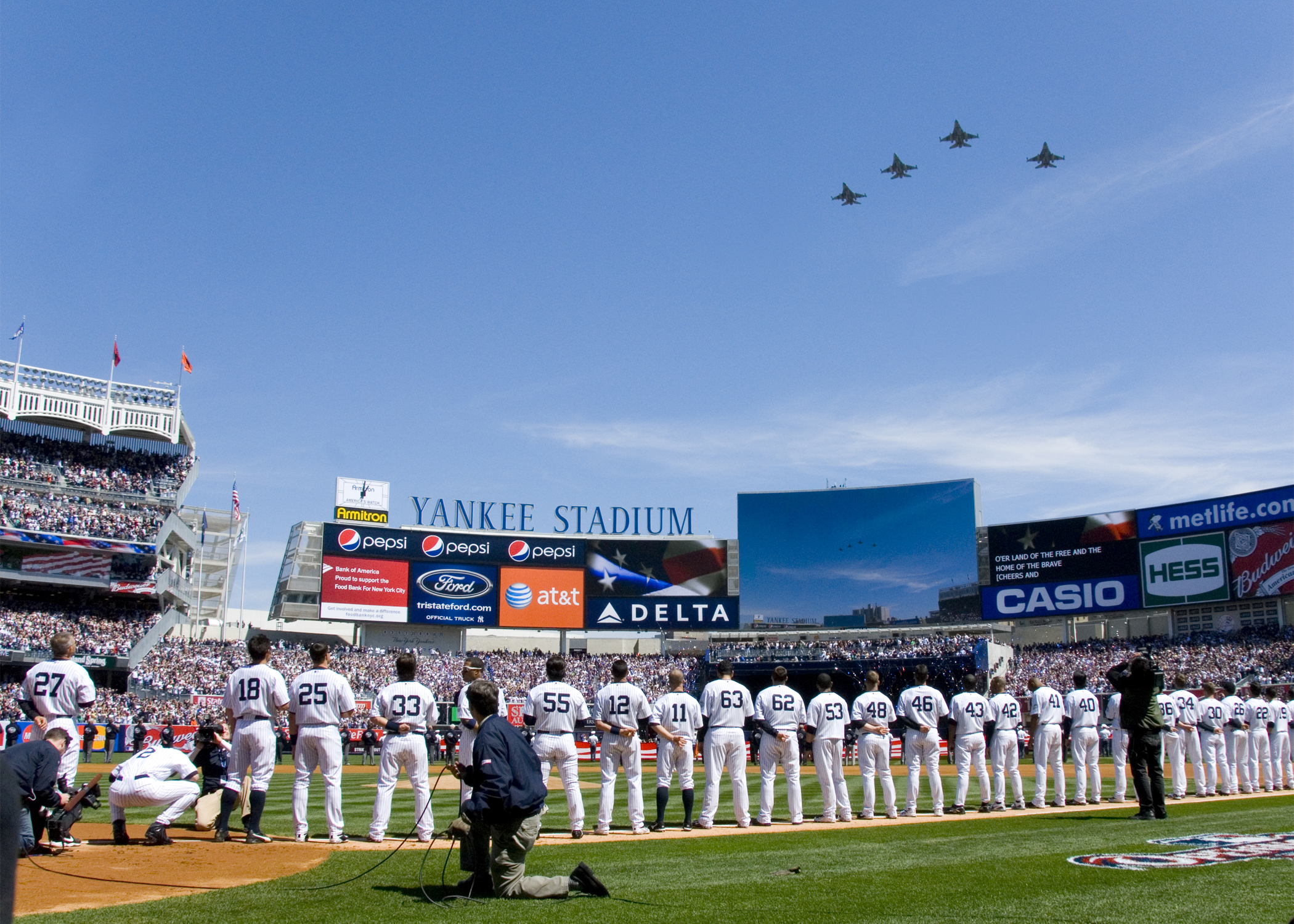F-16 jets fly over Yankee Stadium as Yankees players line up on Opening Day, home of Polymarket's prediction market sports sponsorship