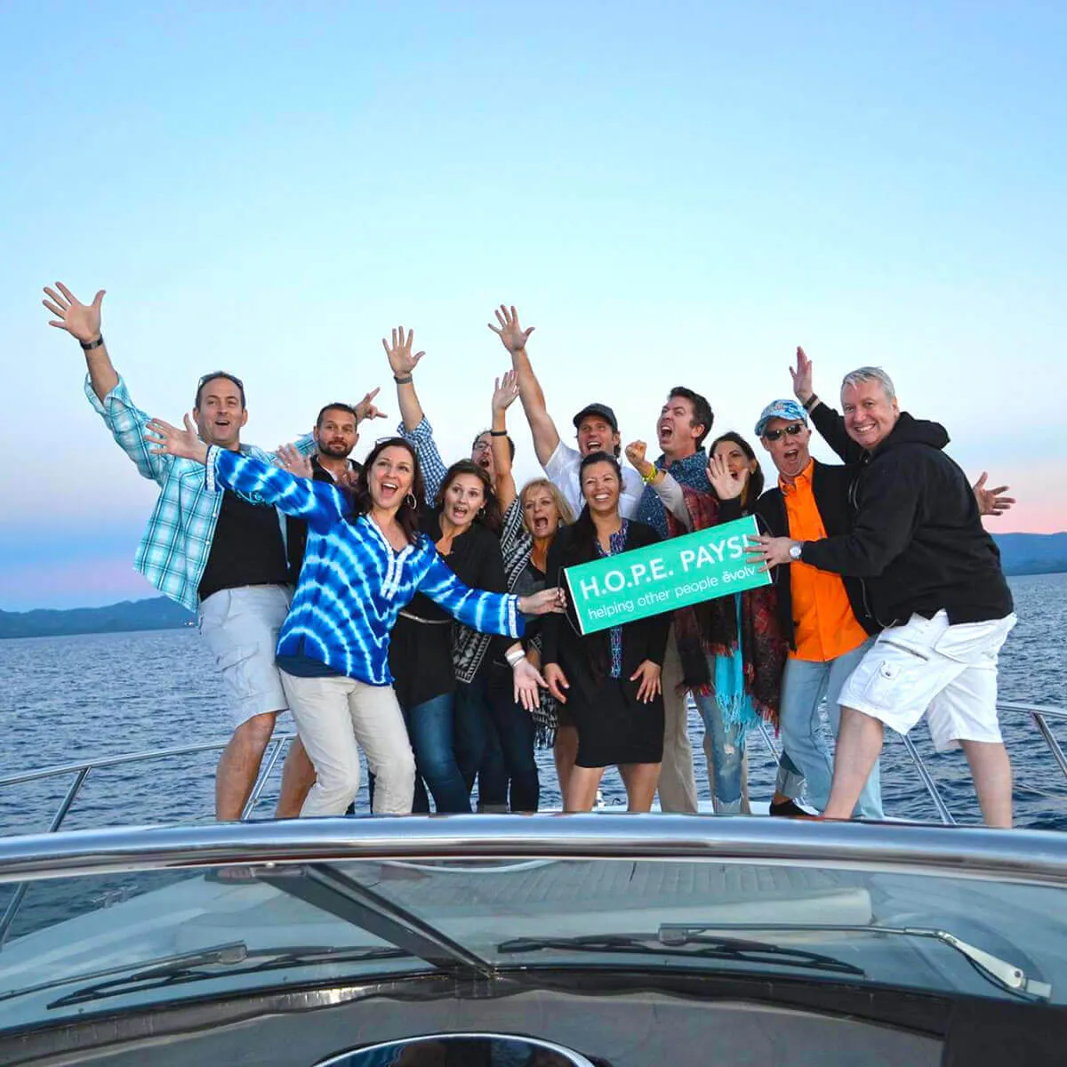 Garrett and Sylvia with people on a boat holding a sign that says "Hope Pays"