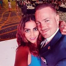 Smiling couple dressed up at an event with colorful background lighting