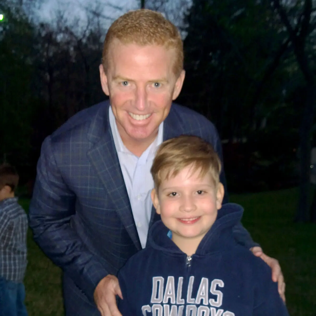 Adult and child in blue jackets, smiling together outdoors at dusk