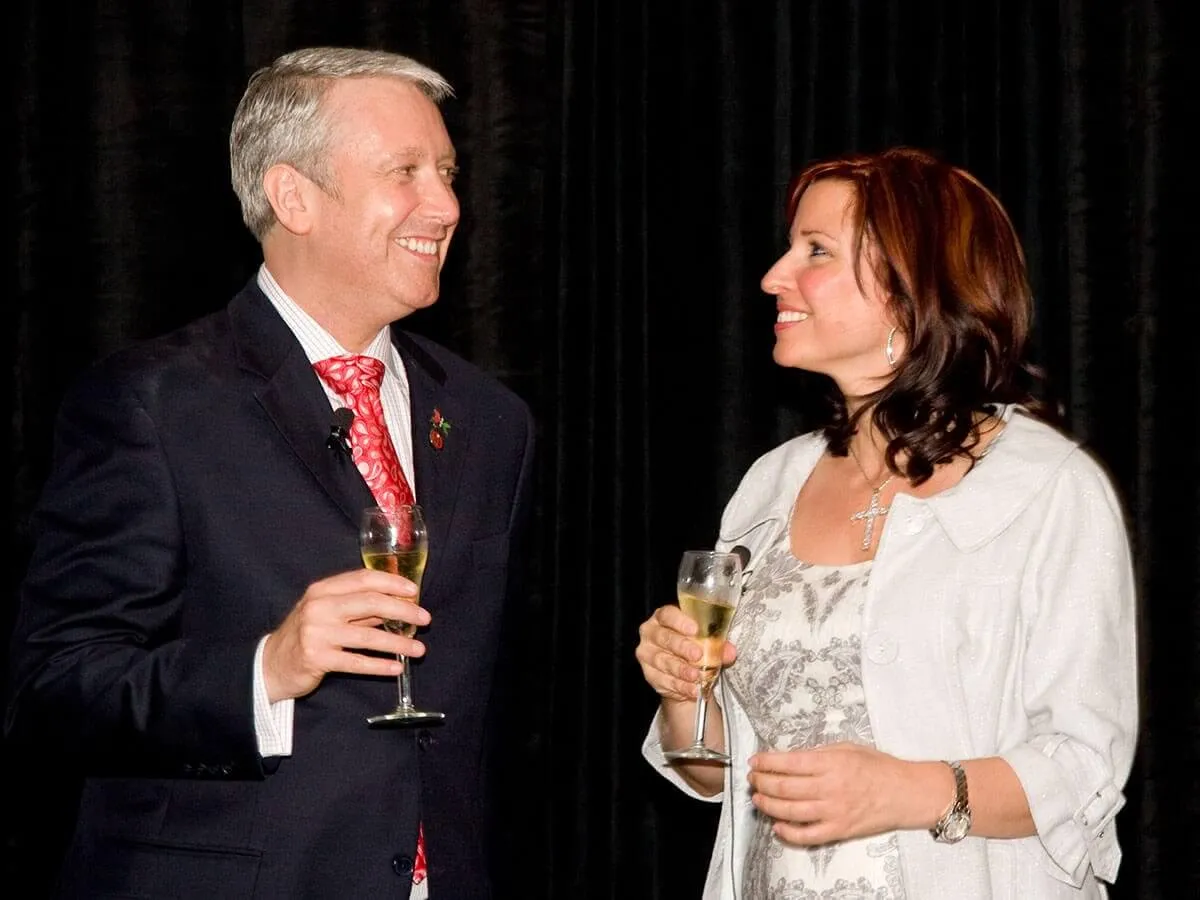 Two people in formal attire smiling and holding champagne glasses