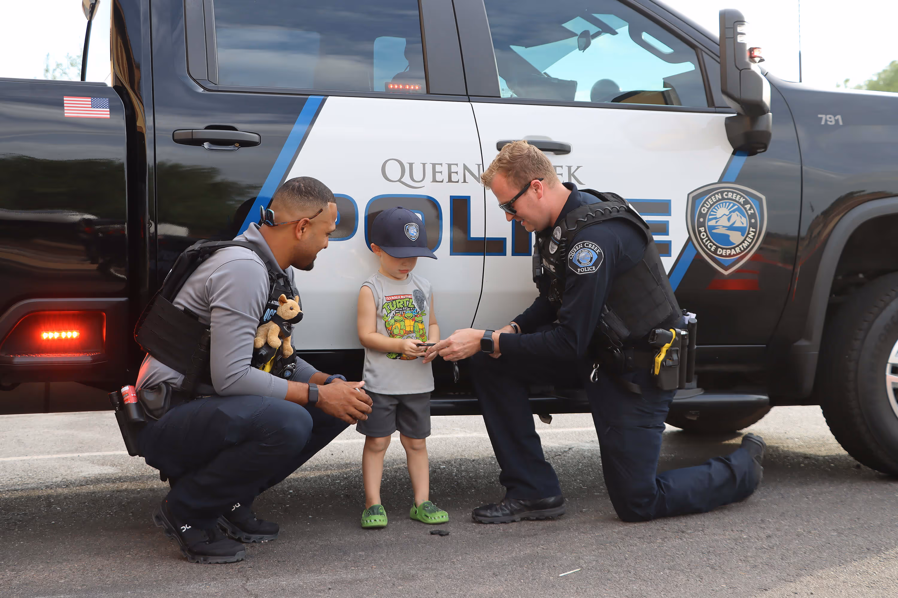 2 officers talking to a child in front of police car