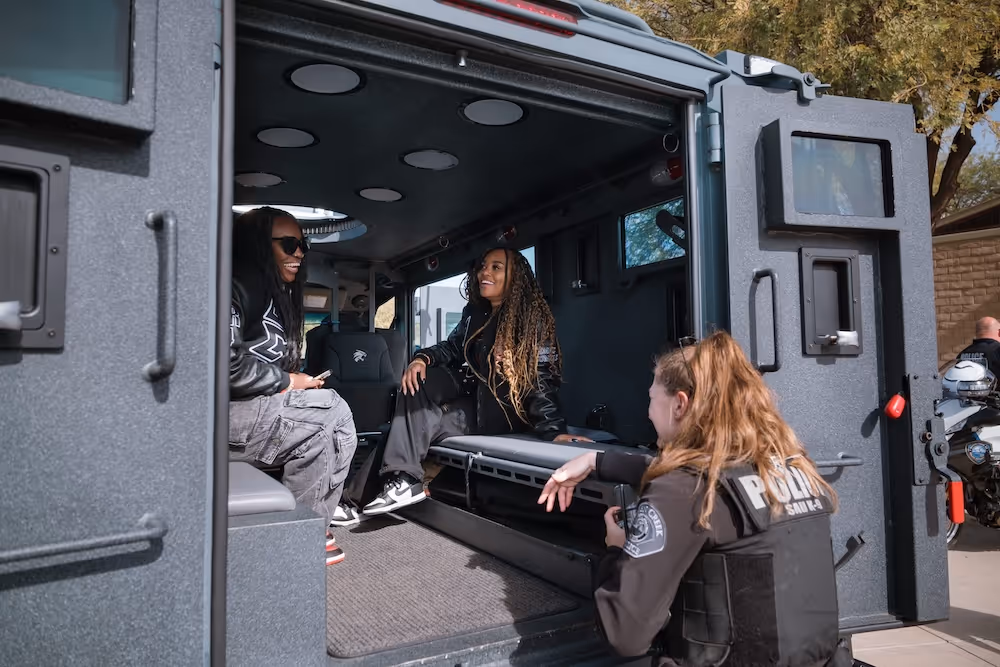 3 females in the police truck smiling