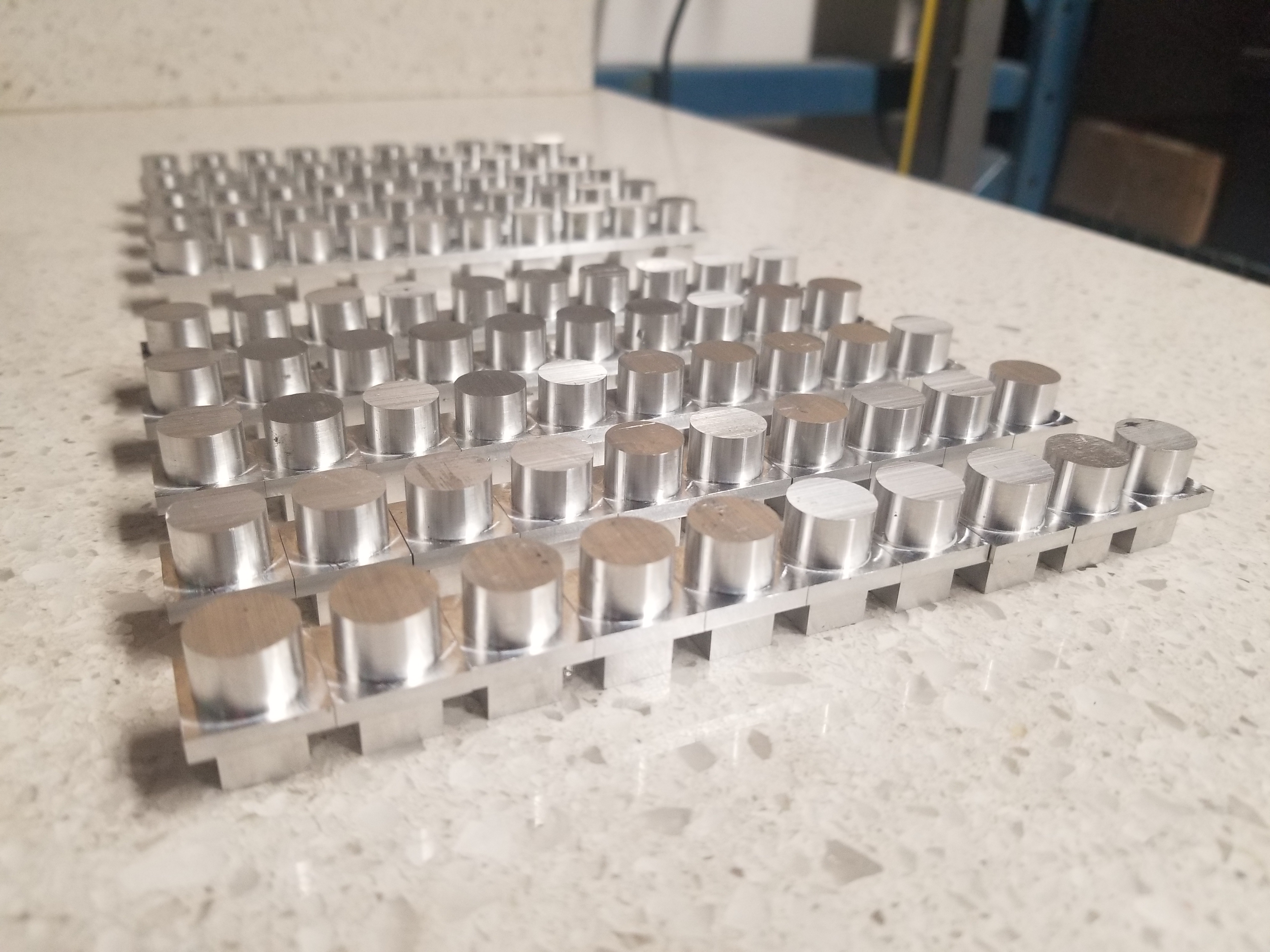 Image of identical machined aluminum parts laid out on table