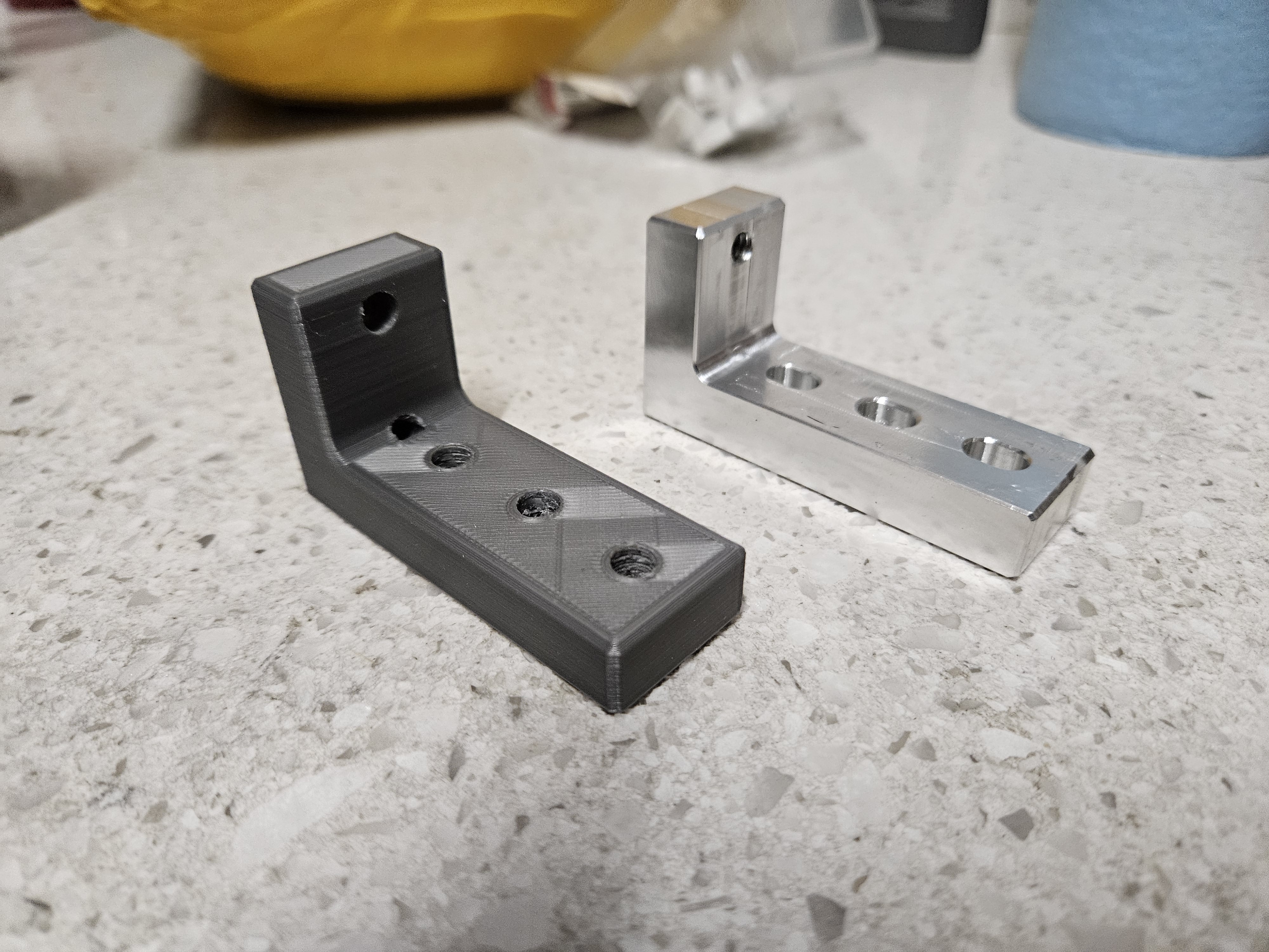 Two right angle bracket parts, one made from 3D printed plastic, the other from aluminum