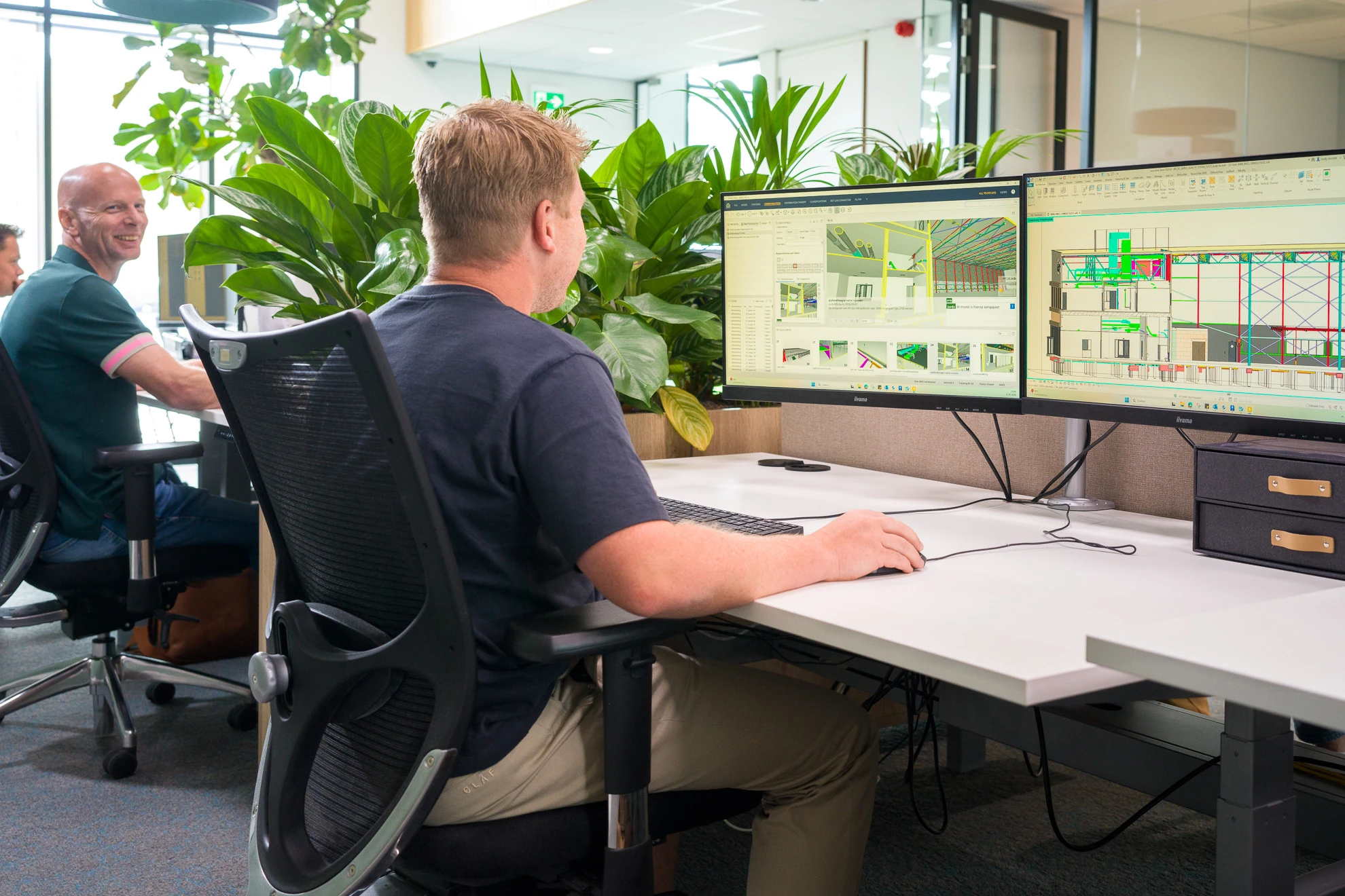 Medewerker van Archifit werkt aan een digitaal gebouwmodel op twee beeldschermen.