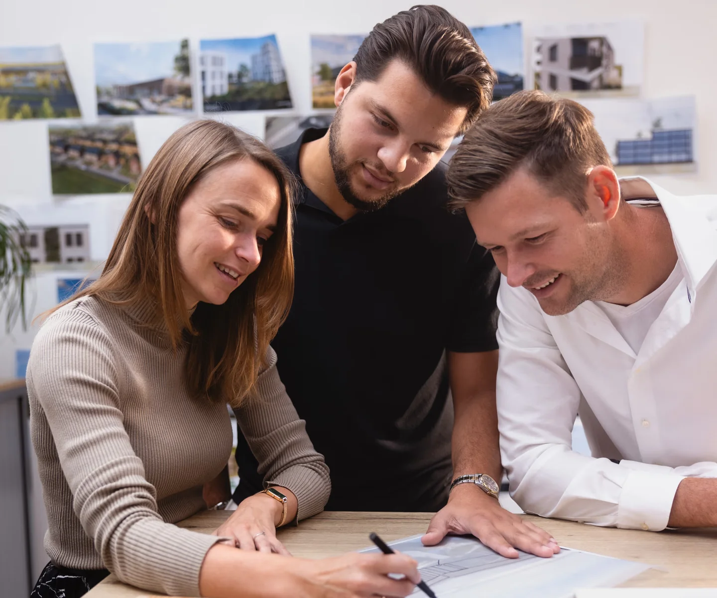 Drie medewerkers van Archifit overleggen samen over een bouwtekening.