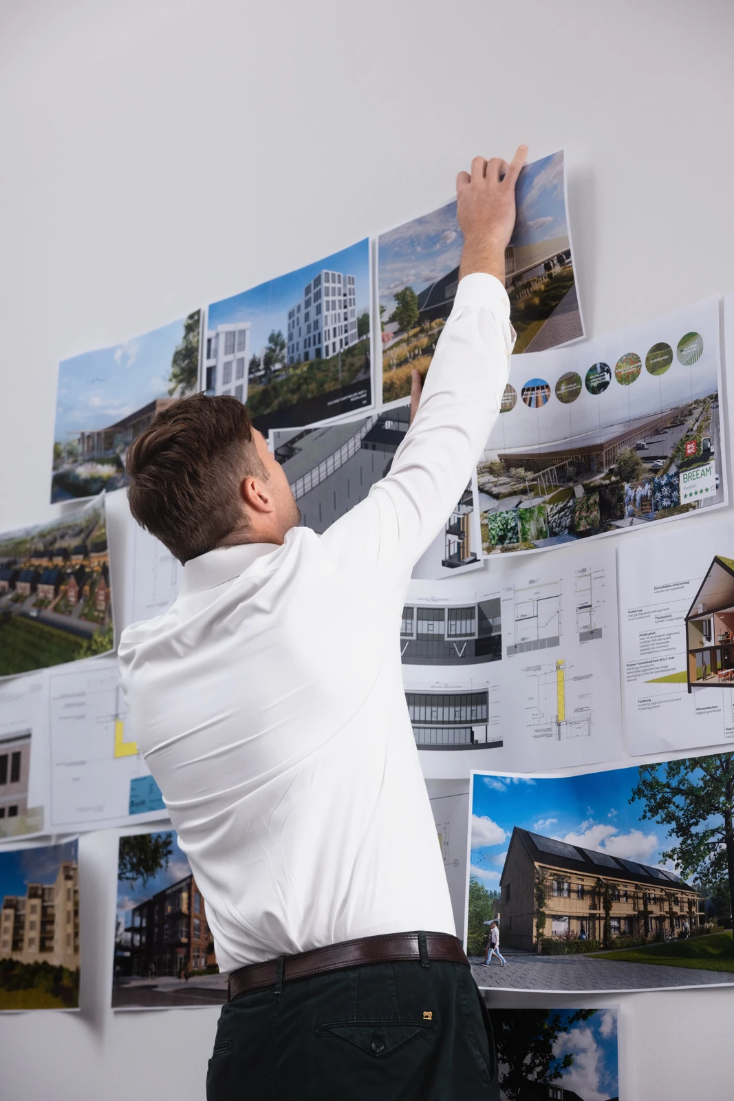 Medewerker van Archifit bekijkt een presentatiebord met gebouwontwerpen en materiaalvoorbeelden.