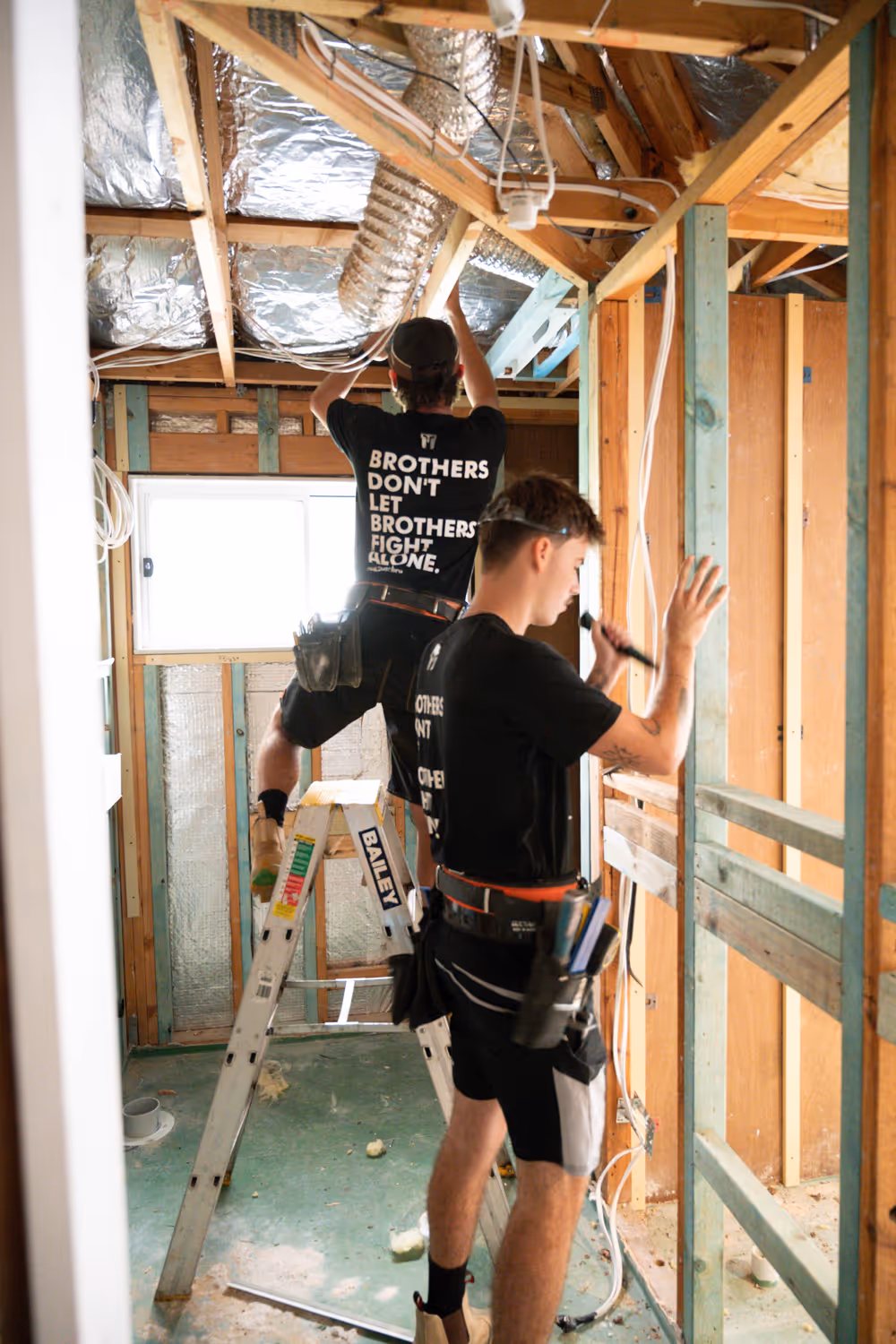 Two men nailing wood in a house