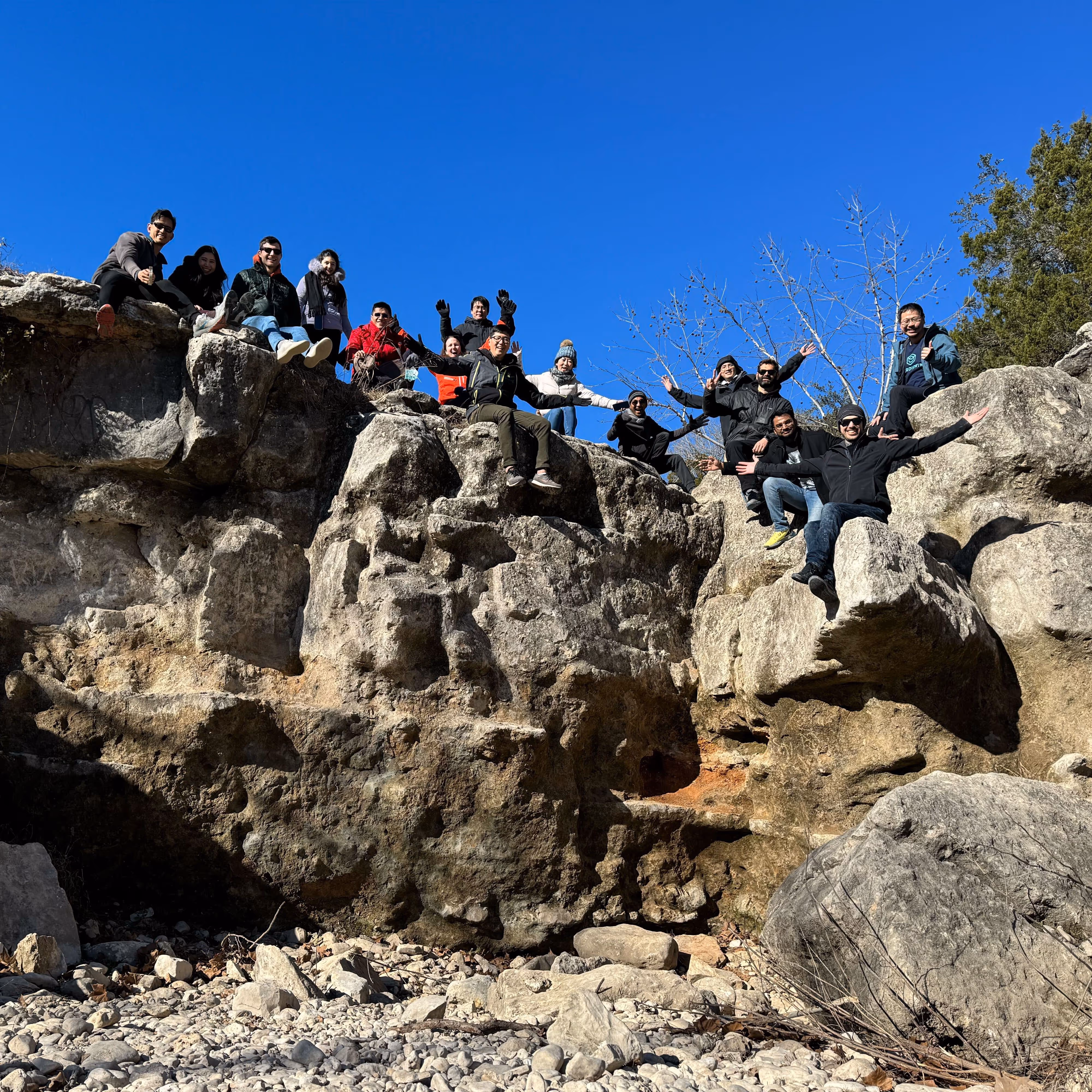 Verdigris team poses on top of a rock formation while on a team hike in Austin, TX