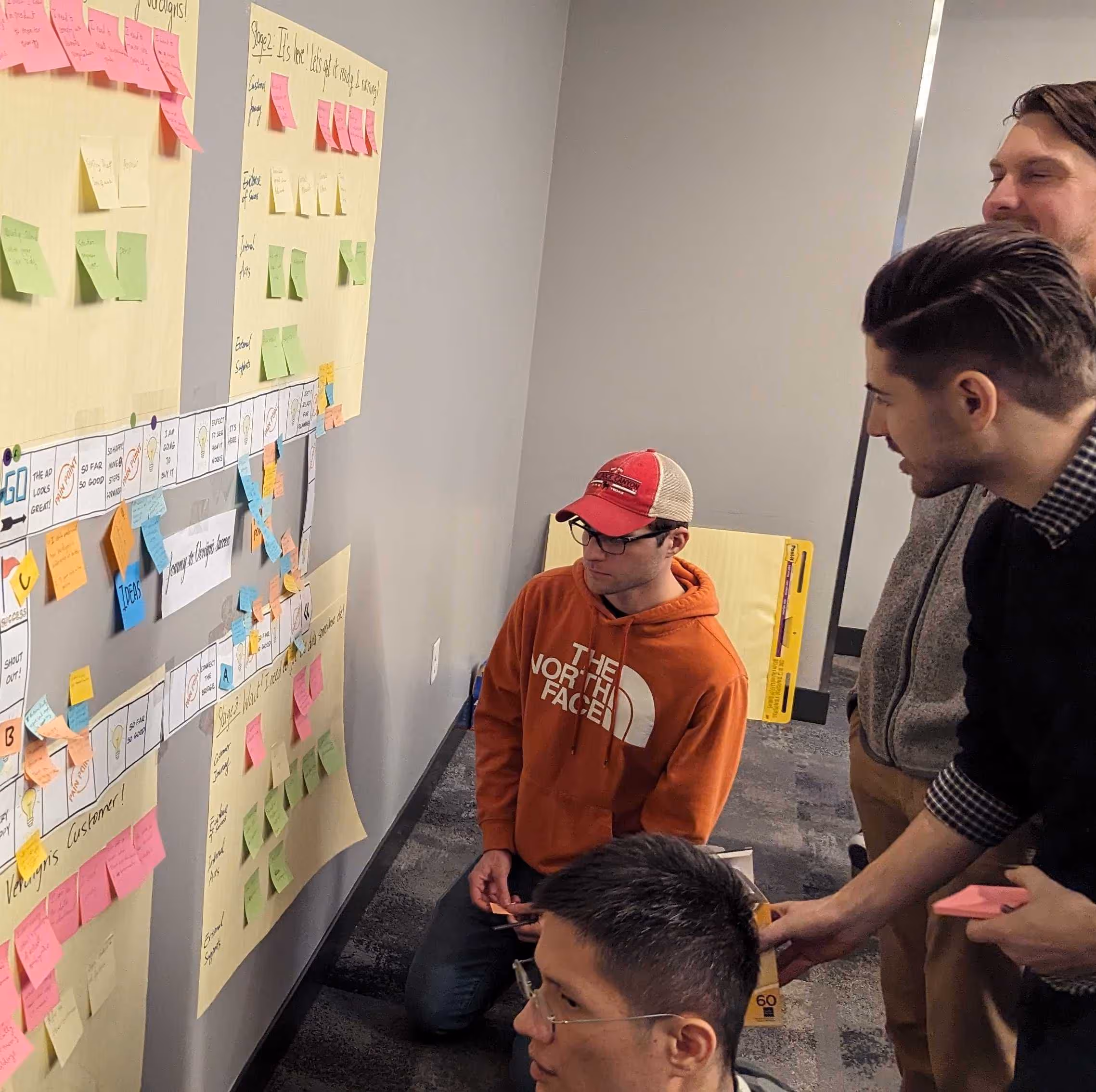 Verdigris team members look at a wall of sticky notes and collaborate on a team building exercise