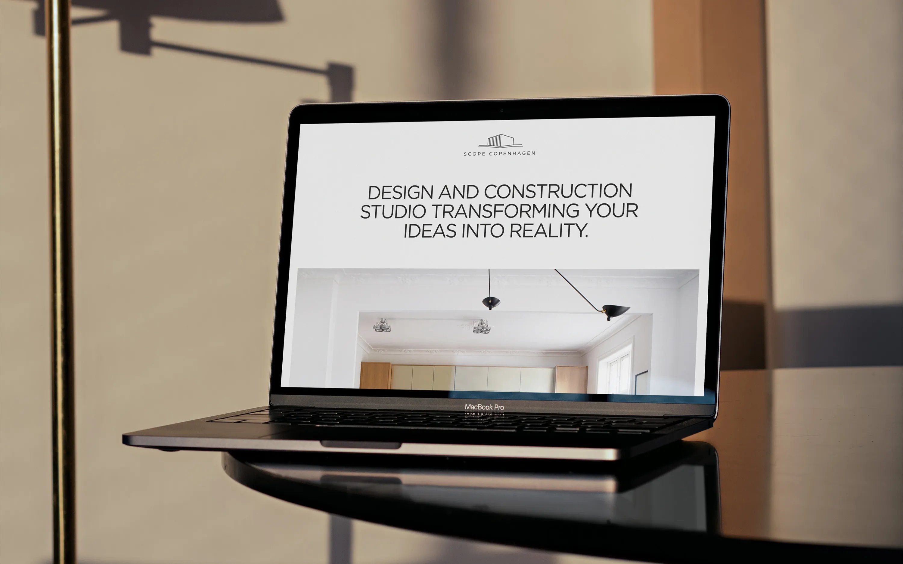 Laptop screen shows Scope Copenhagen website with text about design and construction studio.