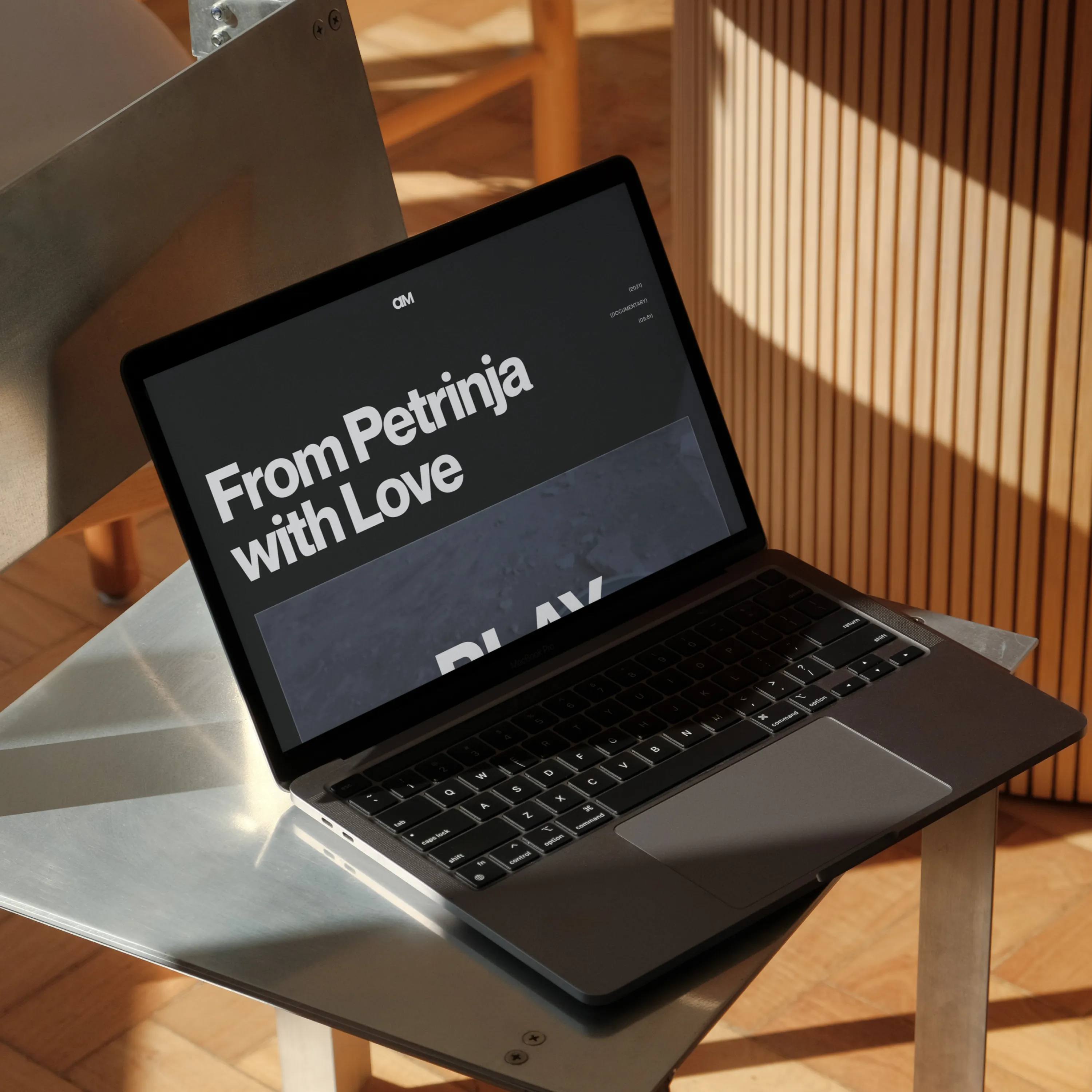 Open laptop on metal chair showing black screen with text 'From Petrinja with Love'.