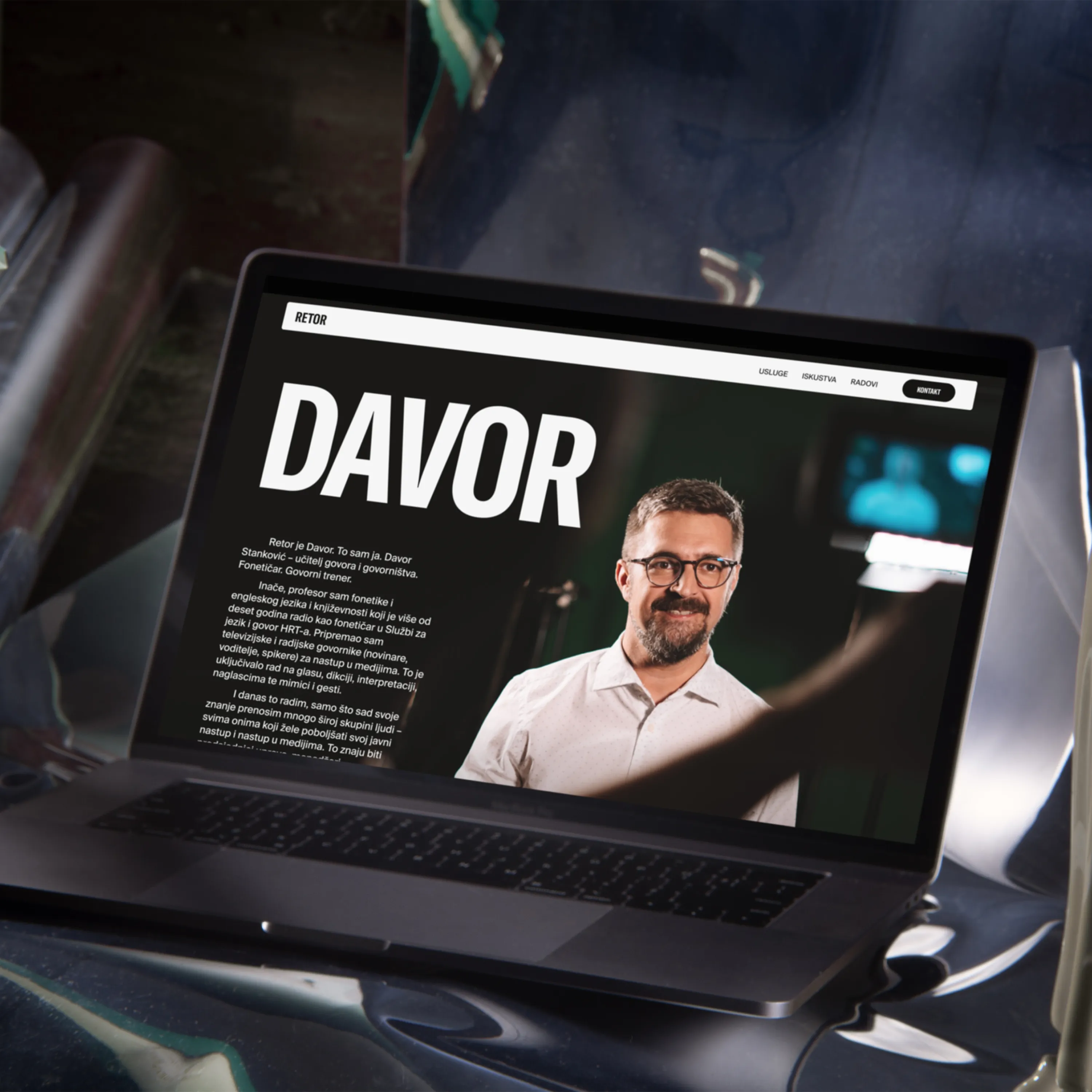 Laptop screen displays a website featuring a man named Davor with a white shirt and glasses.