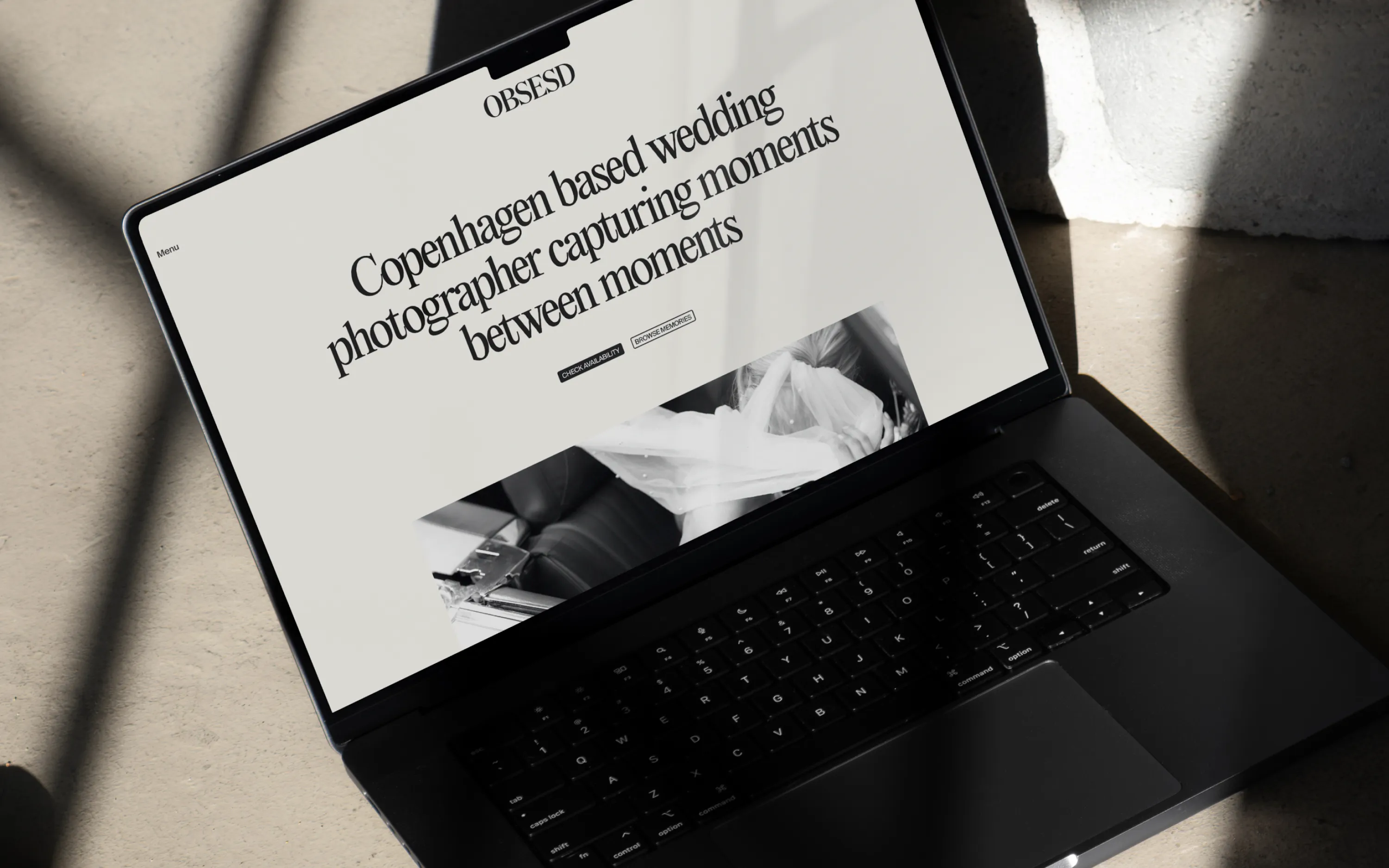 Laptop displaying a website for OBSESD, a Copenhagen-based wedding photographer capturing moments.