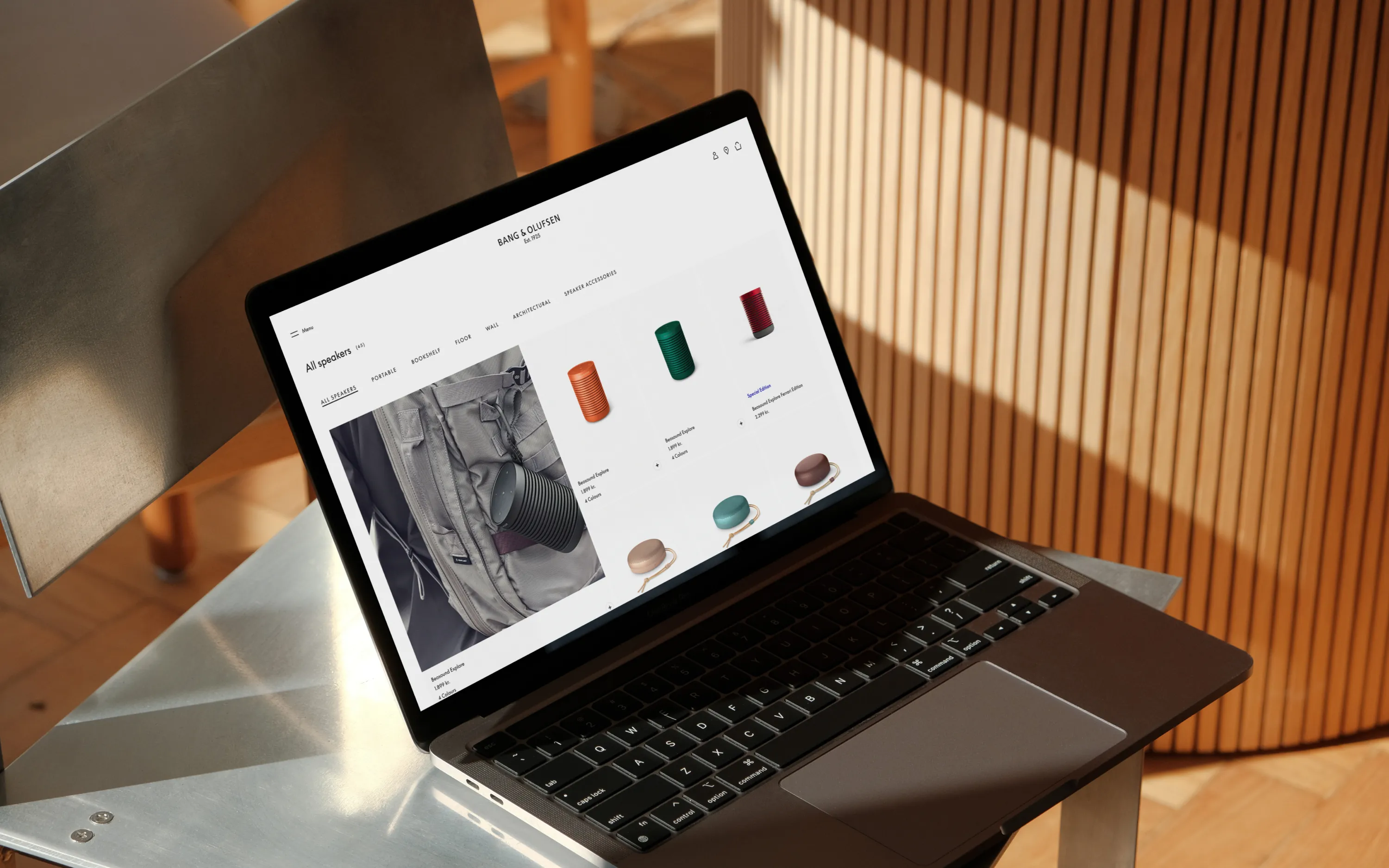 Laptop showing Bang & Olufsen website with images of portable speakers in different colors.