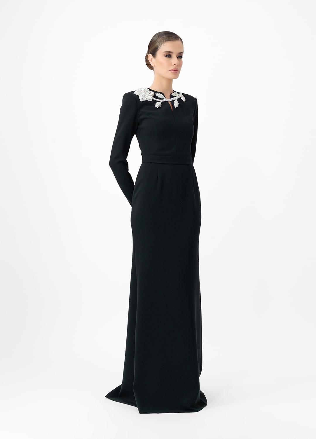Black dress MA2025P20022 BL- Long sleeve maxi dress with decorative belt, embellished with stone roses. Zipper in the center of the back.
