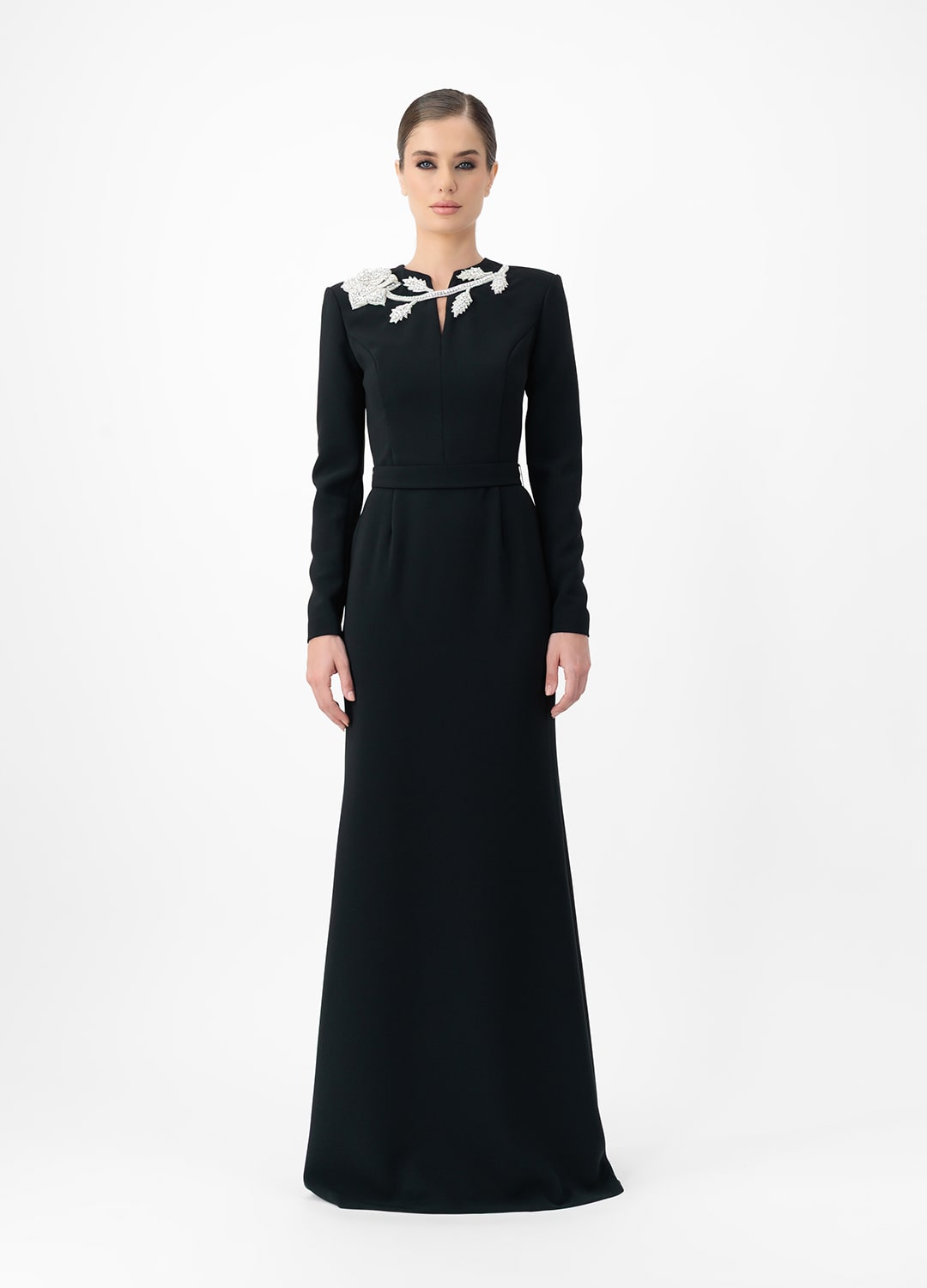 Black dress MA2025P20022 BL- Long sleeve maxi dress with decorative belt, embellished with stone roses. Zipper in the center of the back.