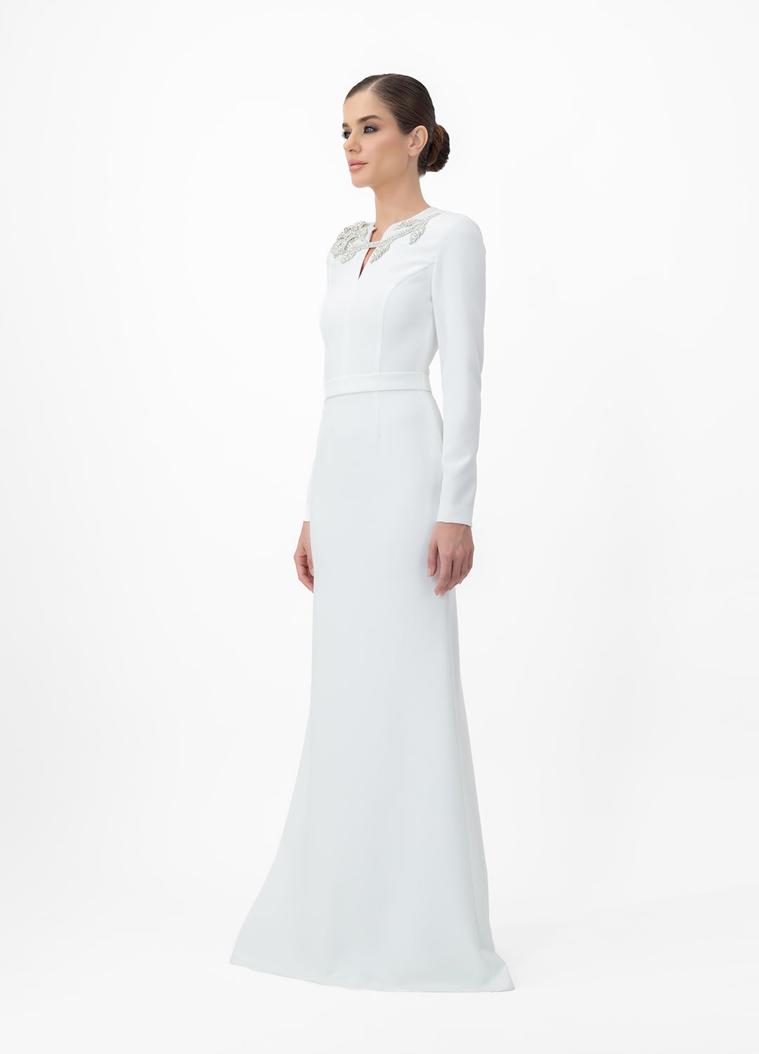 White dress MA2025P20022 W- Long sleeve maxi dress with decorative belt, embellished with stone roses. Zipper in the center of the back.