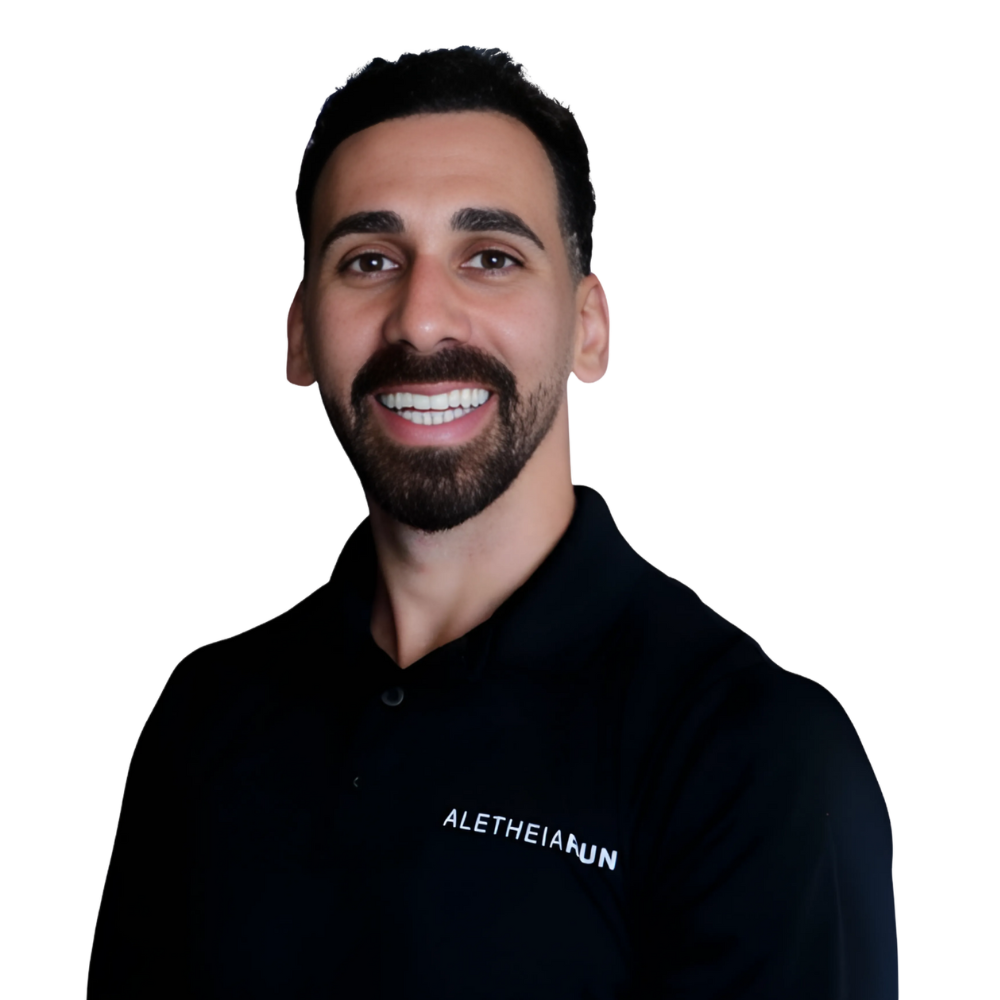 Smiling man with dark hair and beard wearing a black polo shirt with Aletheia UN logo.
