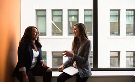 Women talking while sitting next to a window