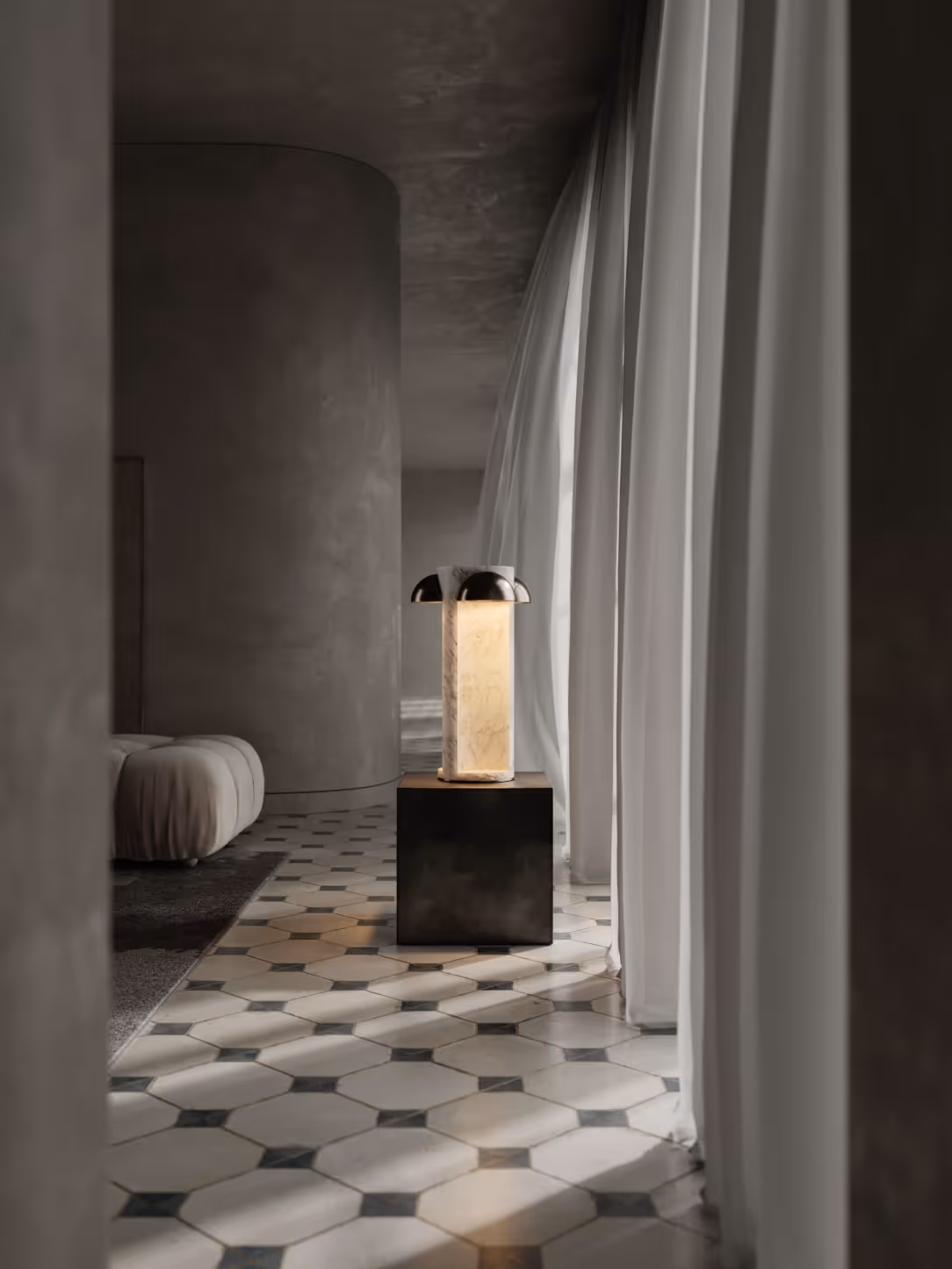 A detailed interior render featuring a modern lamp on a pedestal. The lamp has a cylindrical shape made of translucent material, allowing warm light to emanate. The setting includes a patterned floor of hexagon tiles, and sheer curtains that softly drape nearby.