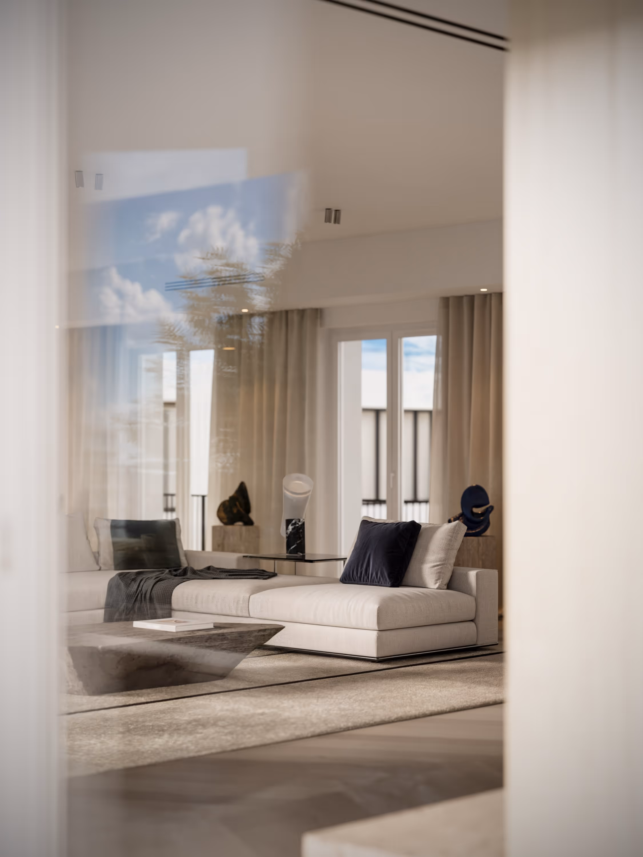 A photorealistic interior render showcasing a sophisticated living room with cream-colored couches, modern art on the wall, and large windows flooding the space with natural light. Ideal for real estate marketing and interior design presentations