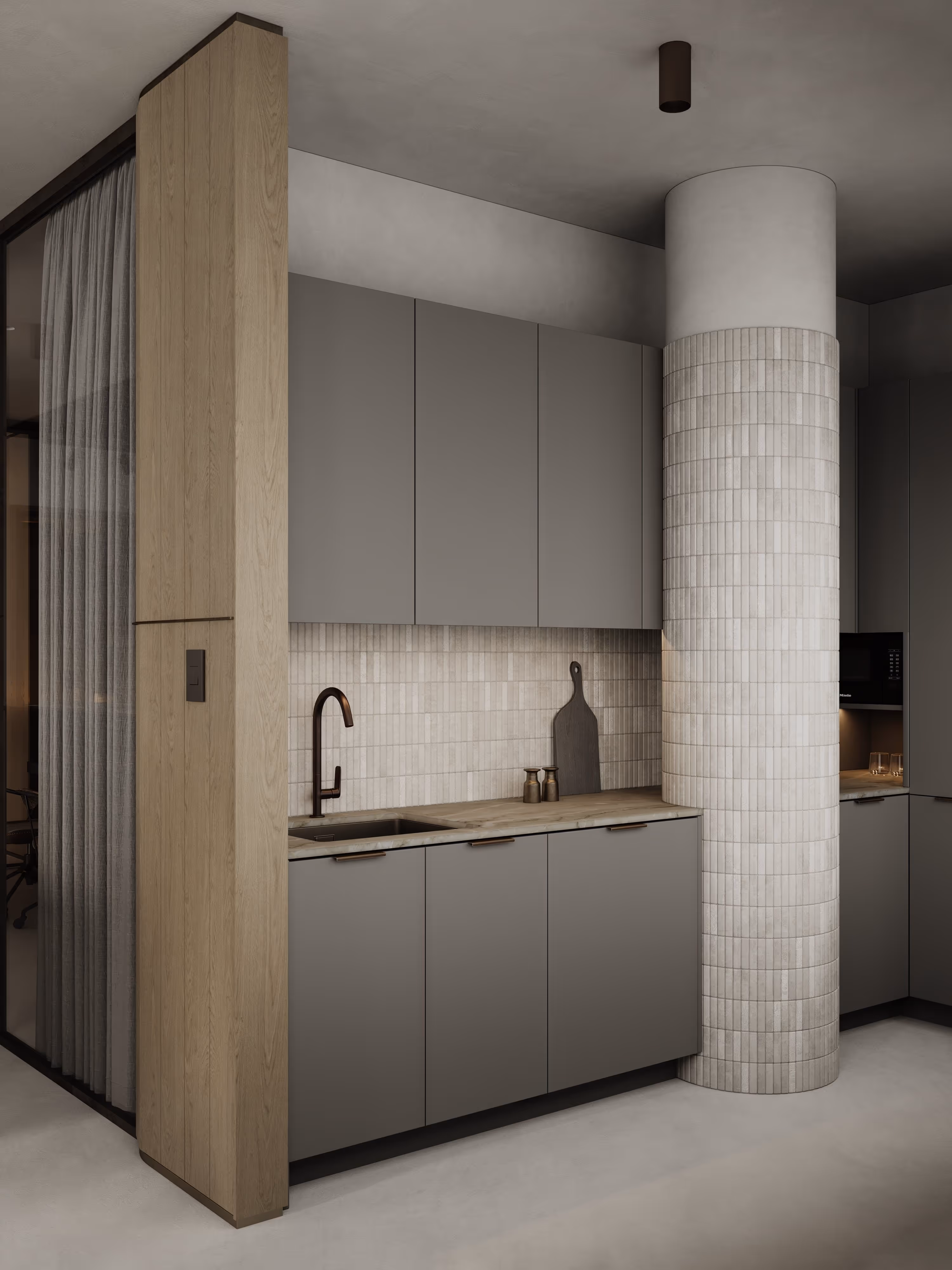 A compact kitchen area with neutral-toned cabinetry and subtle lighting, complemented by a column with a textured tile finish. The design maintains simplicity and functionality with clean lines and a modern aesthetic.