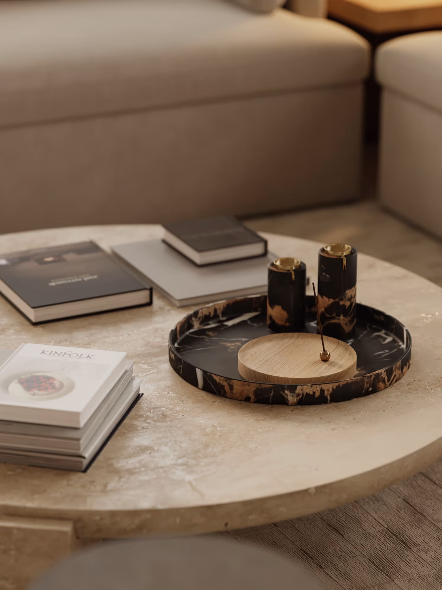 A close-up of a circular marble coffee table with decorative items including books and elegant black and gold cups, placed on a textured surface.