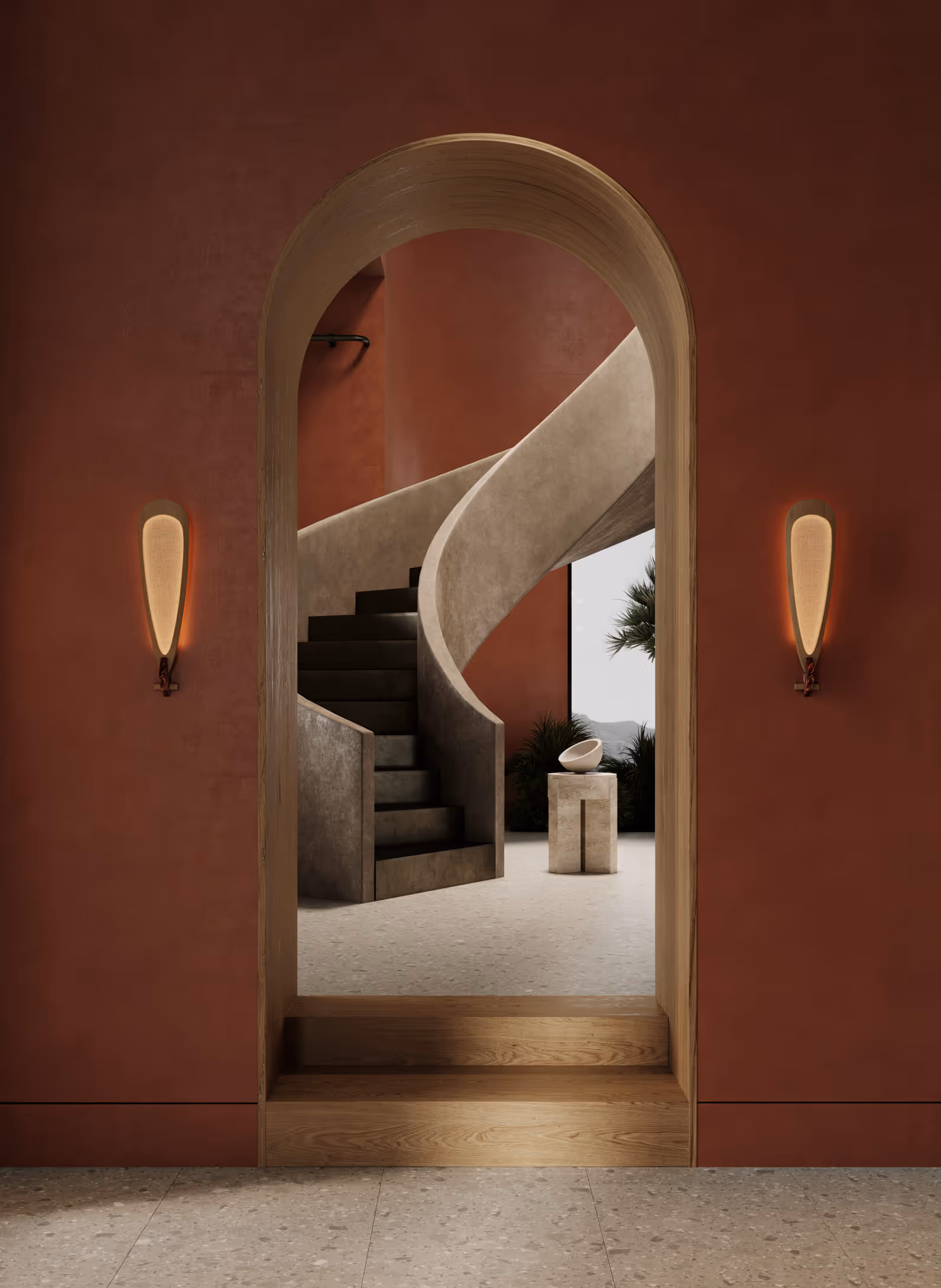 A warm-toned interior view with an archway leading to a curved staircase. Two minimalist wall sconces flank the entryway, blending the rustic red walls with soft, contemporary lighting.