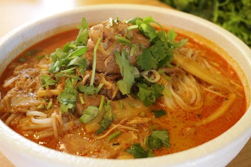 there is a bowl of soup with meat and vegetables in it