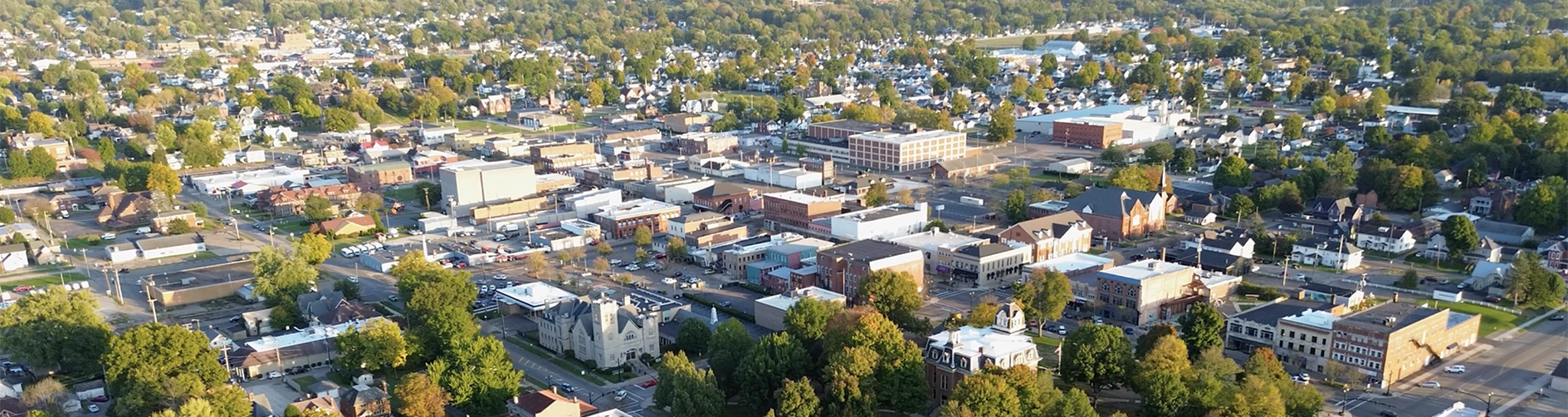 Aerial view of a small town with buildings, houses, trees, and streets in early autumn.