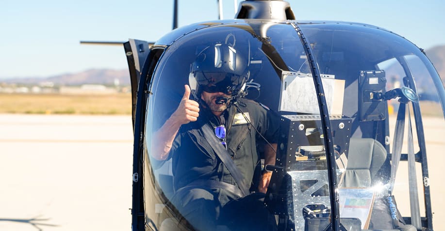 Man giving a thumbs up from inside a helicopter