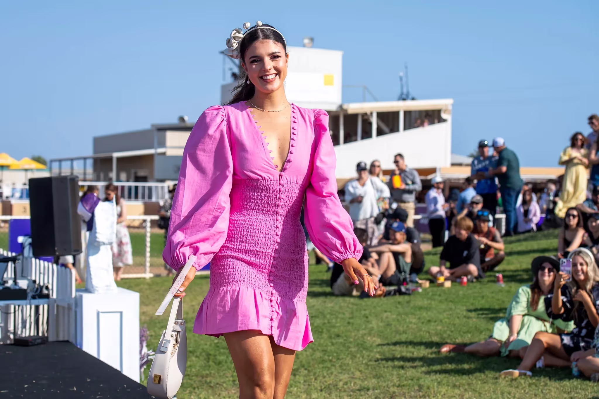 Ladies Day participant smiling and walking along stage in front of crowd