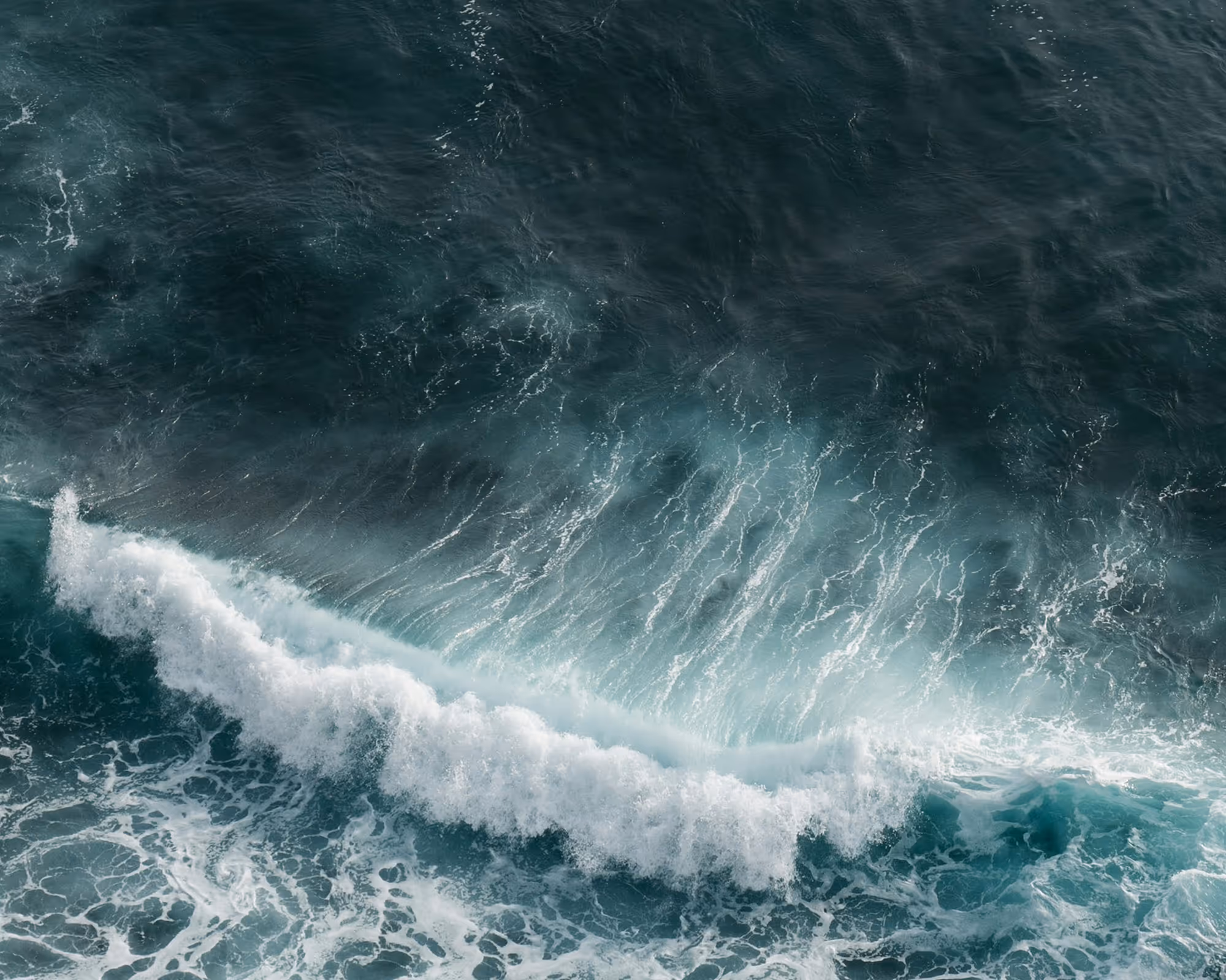 Top-down view of textured deep-blue ocean surf, symbolising Agulhas FS’s guided financial direction.