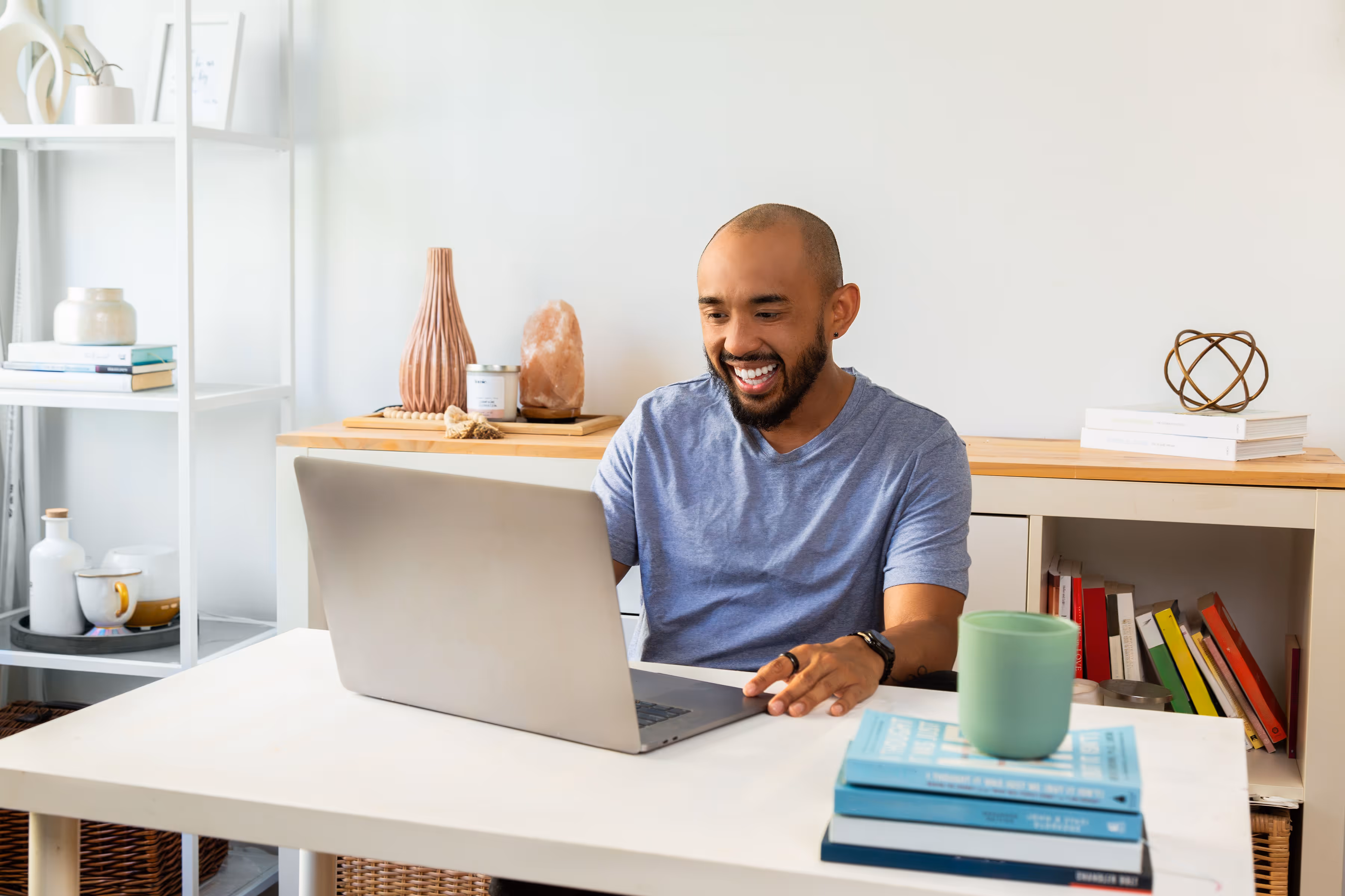 A person sitting at their desk and looking at their laptop while smiling