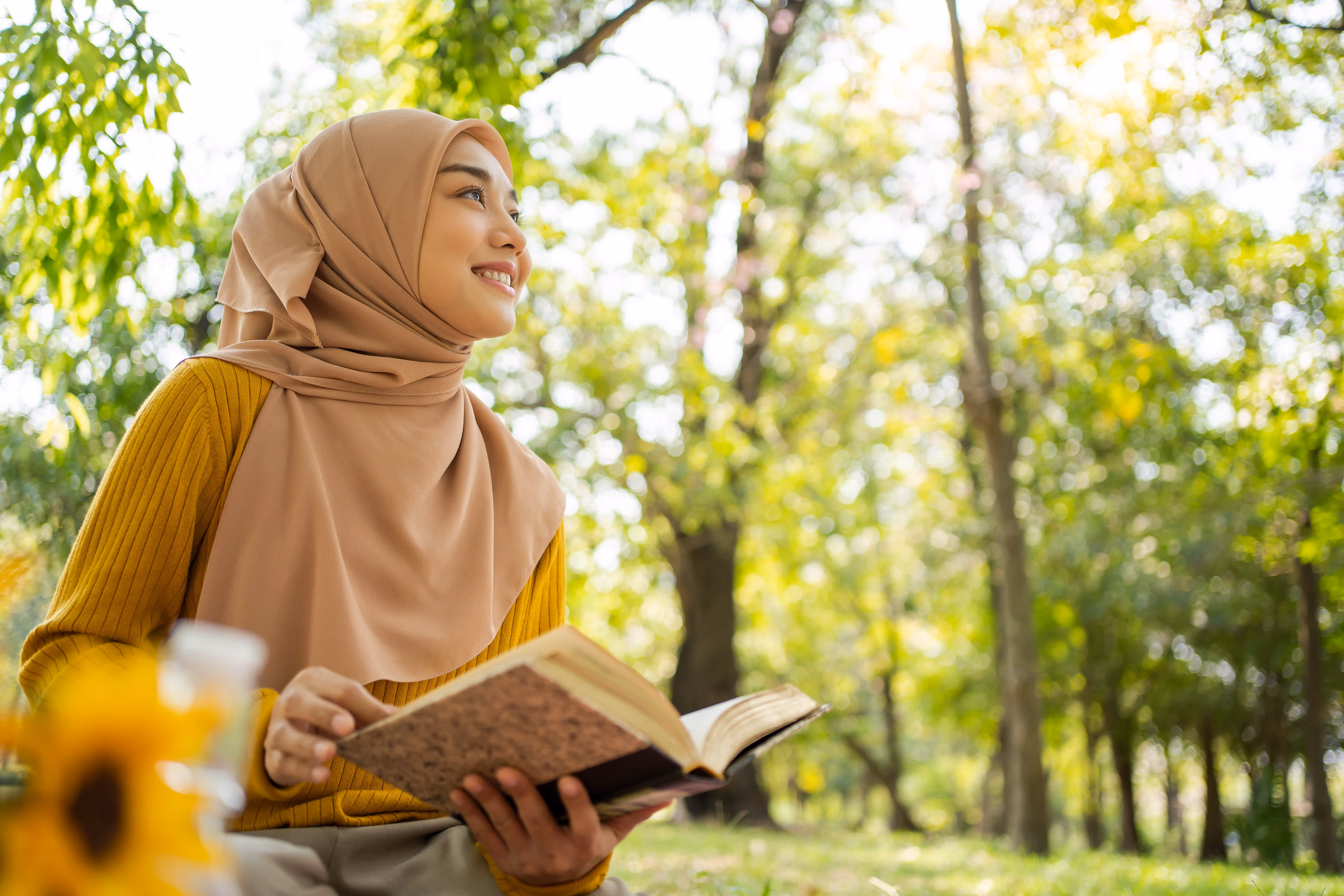 A person in the middle of a tree cluster, looking around and holding a notebook
