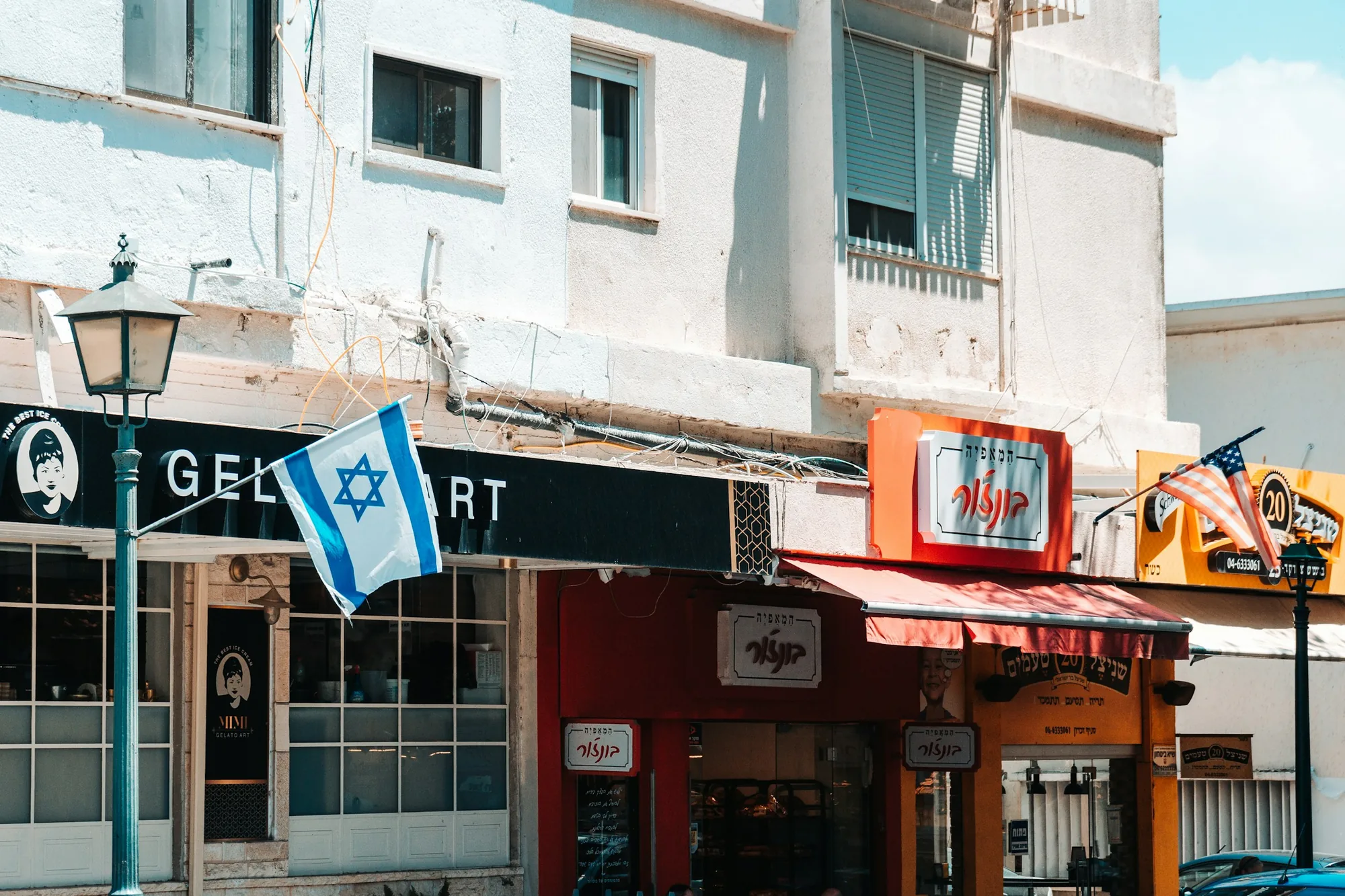 פינת רחוב עם חנויות ודגל ישראל