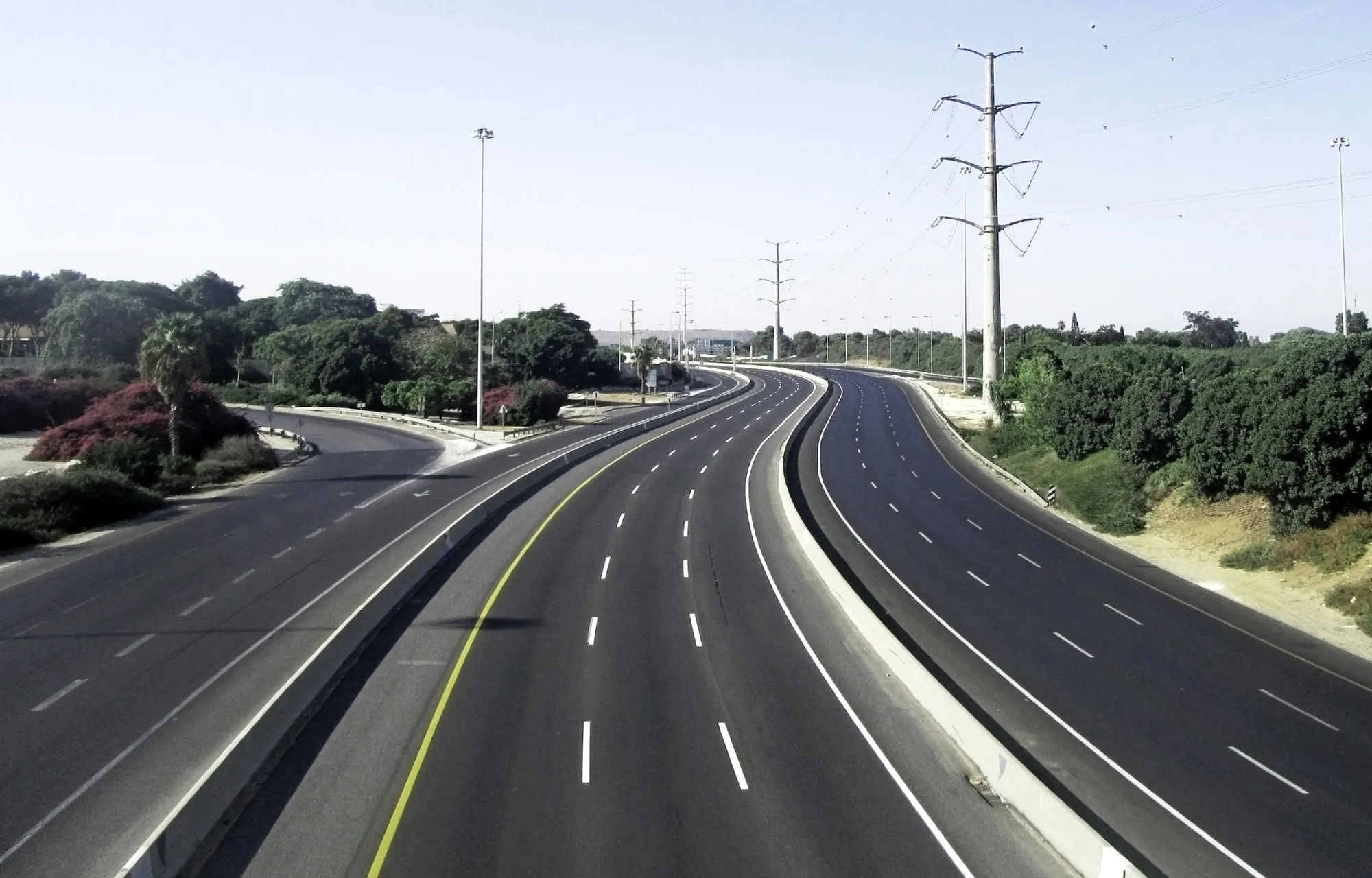 כביש מהיר רחב ריק בין עצים וקווי חשמל