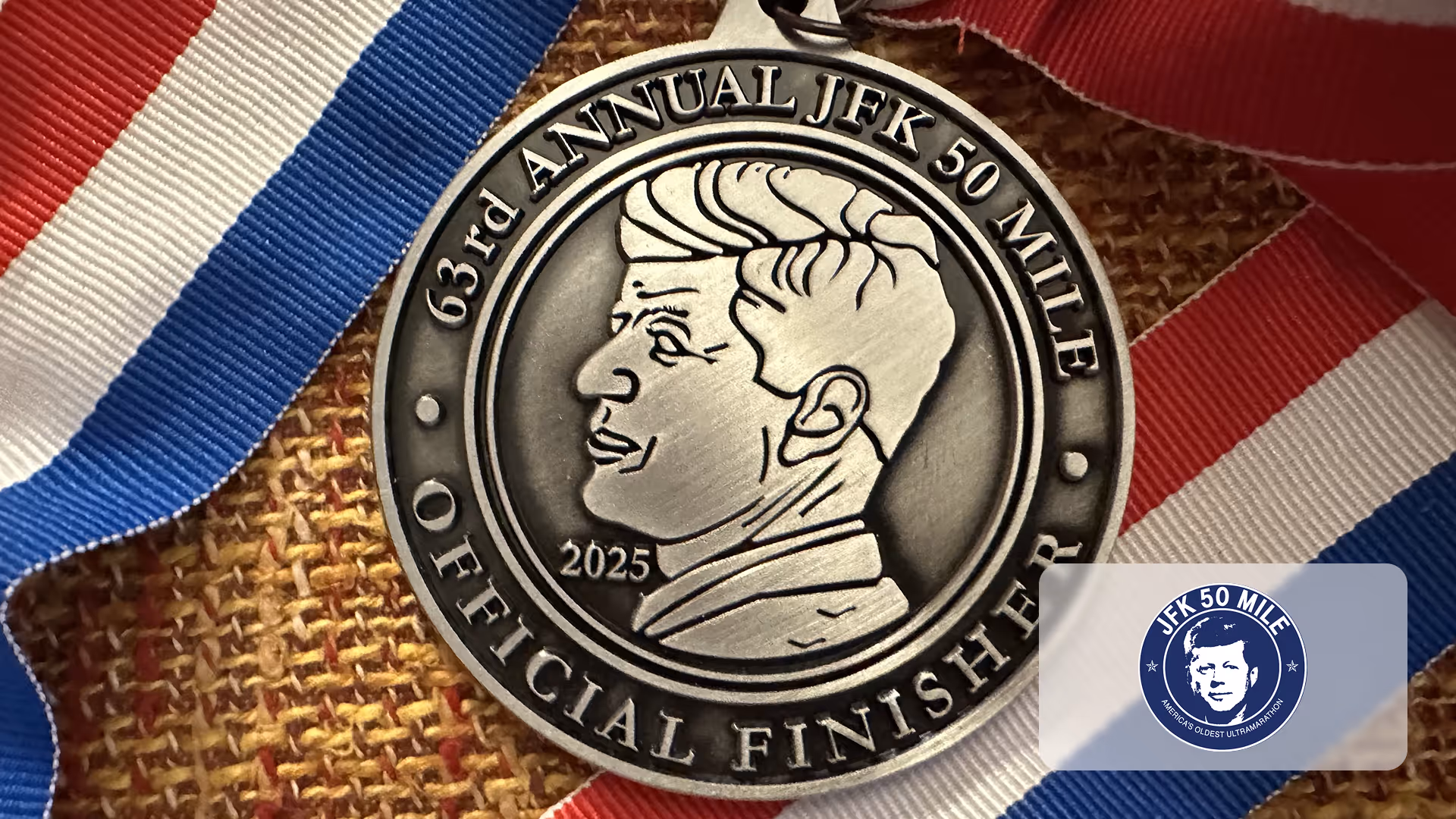 Medal with JFK profile and text '63rd Annual JFK 50 Mile Official Finisher 2025' on red, white, blue ribbon.