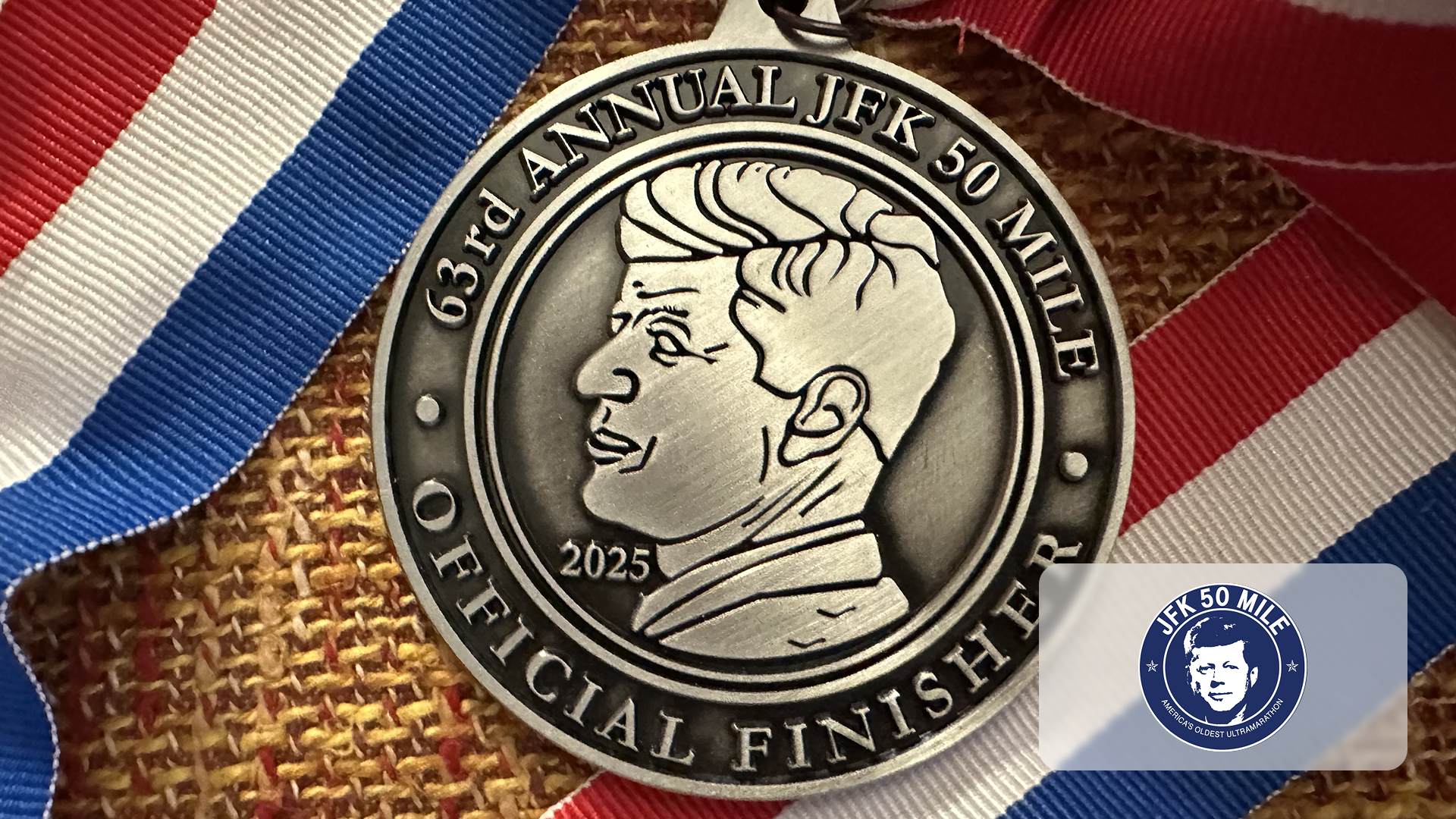 Medal with JFK profile and text '63rd Annual JFK 50 Mile Official Finisher 2025' on red, white, blue ribbon.