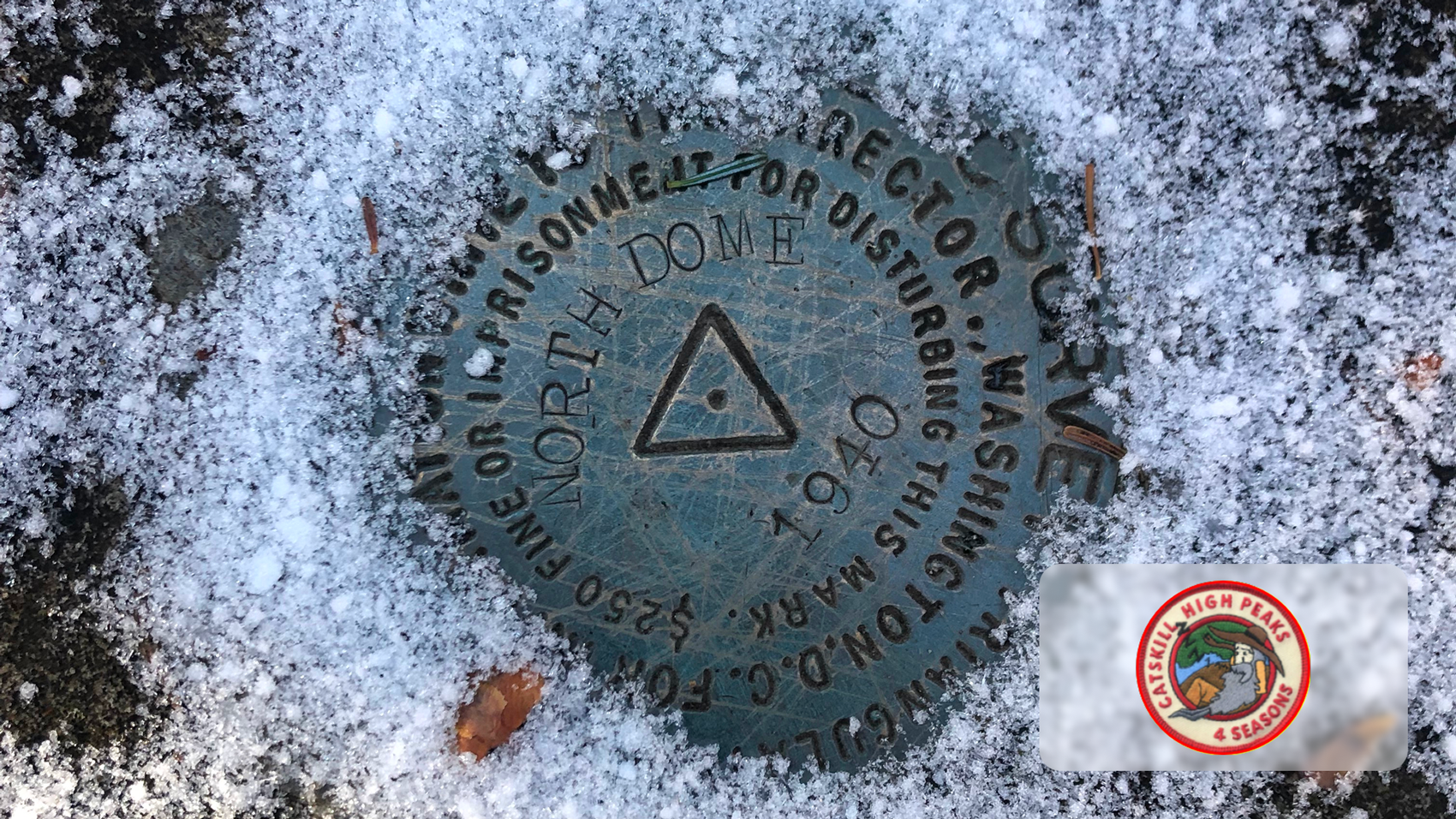 Metal survey marker embedded in snow, labeled North Dome 1940 with surrounding text.