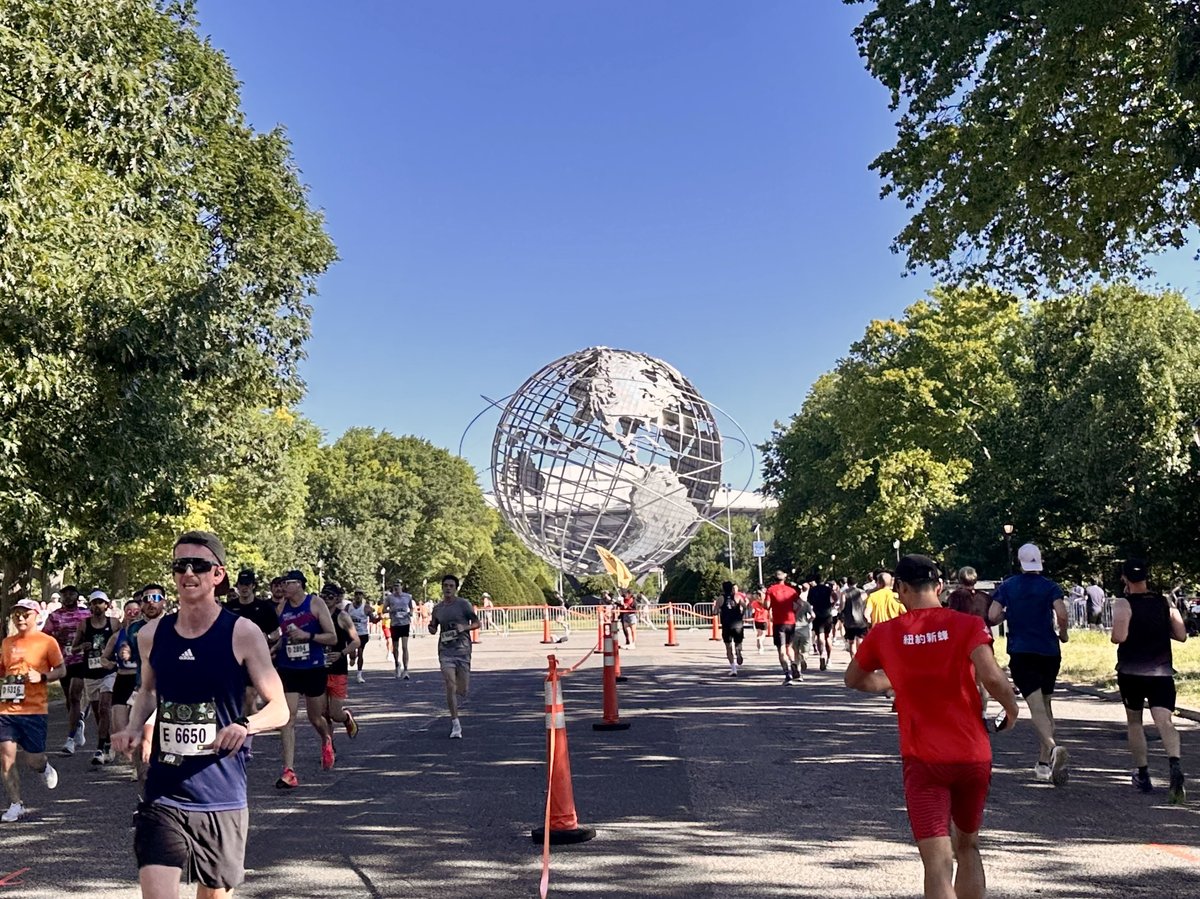 Runners streaming past the Unisphere on a clear June morning at the Queens 10K