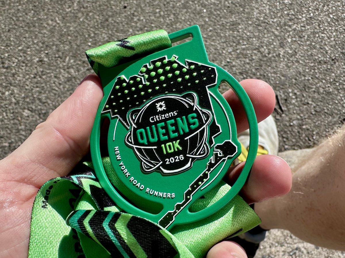 The green Queens 10K finisher medal for 2026, featuring the Unisphere graphic on a bright green ribbon