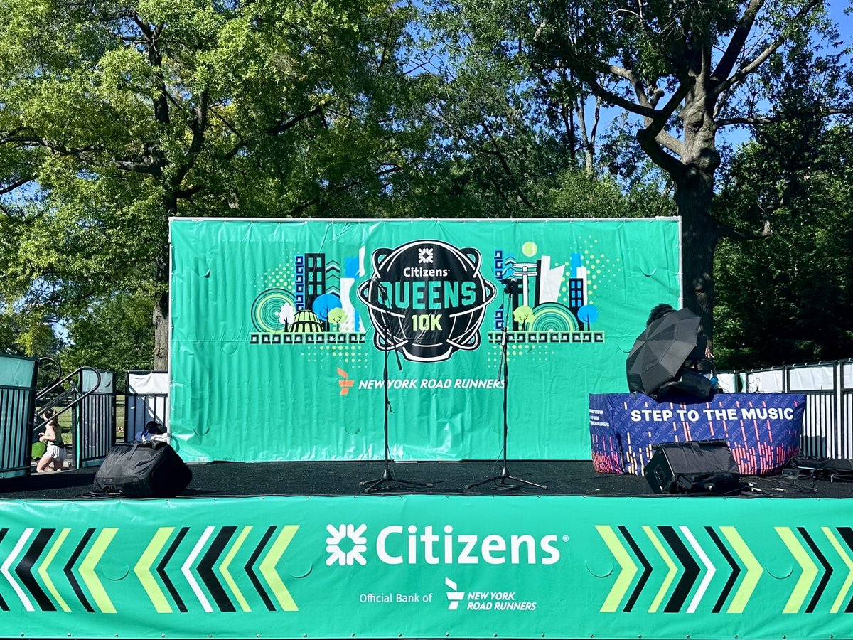 The Citizens Queens 10K main stage set up in the park, bright green branding, speakers ready