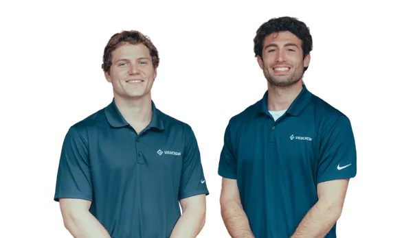 Two smiling men standing side by side wearing navy blue polo shirts with VERSACAM logos.