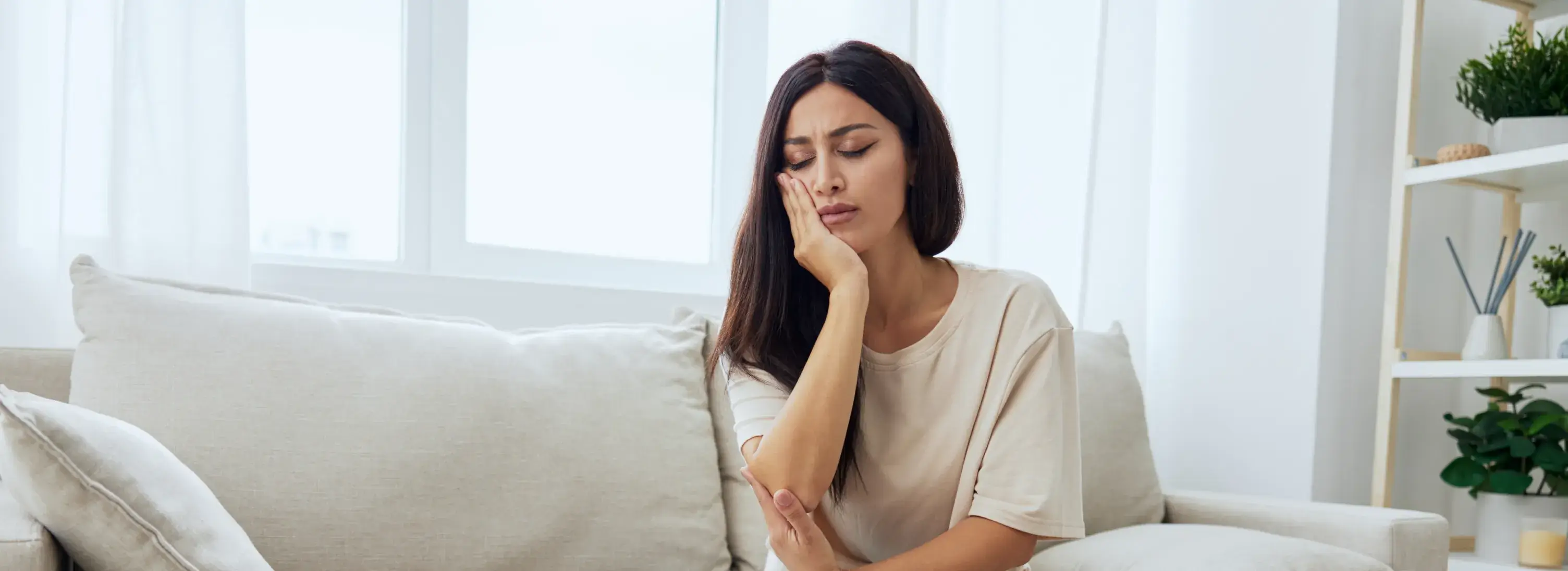 A woman sitting on a couch with her hand on her chin.