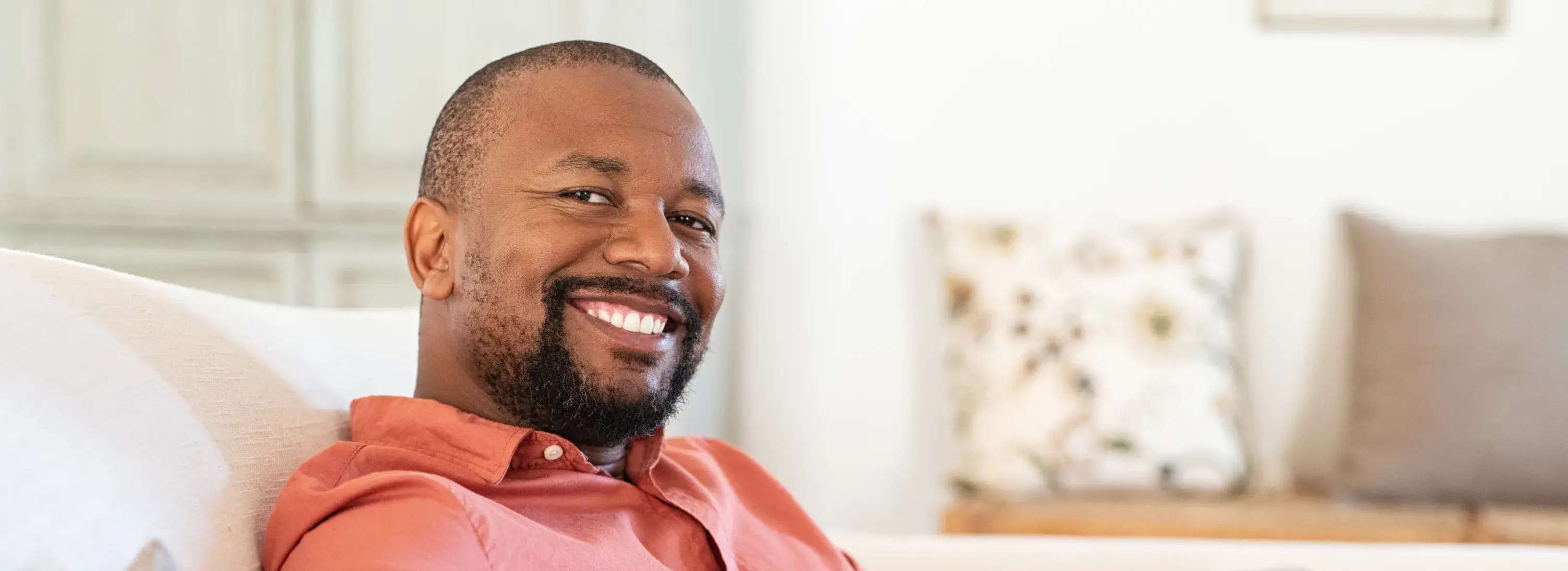 A man sitting on a couch smiling at the camera.