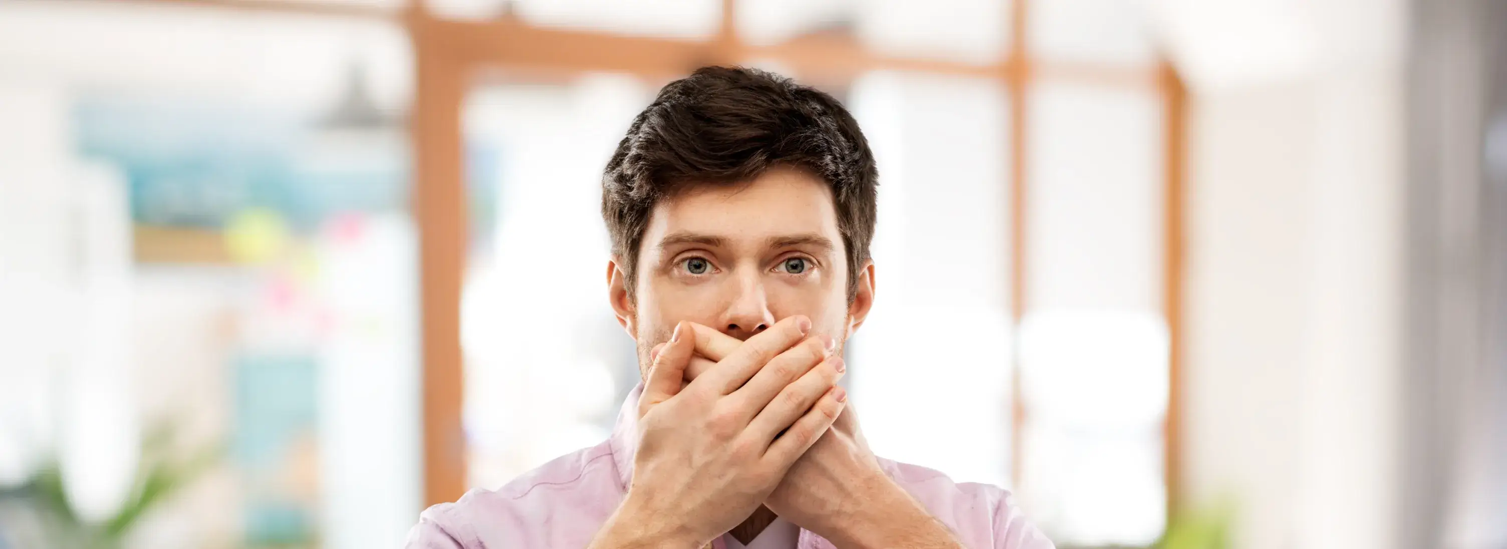 A man covers his mouth with his hands.